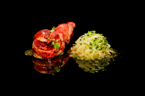 Un plat de rosbif roulé aux herbes accompagné de purée de pommes de terre, presenté sur un fond noir.