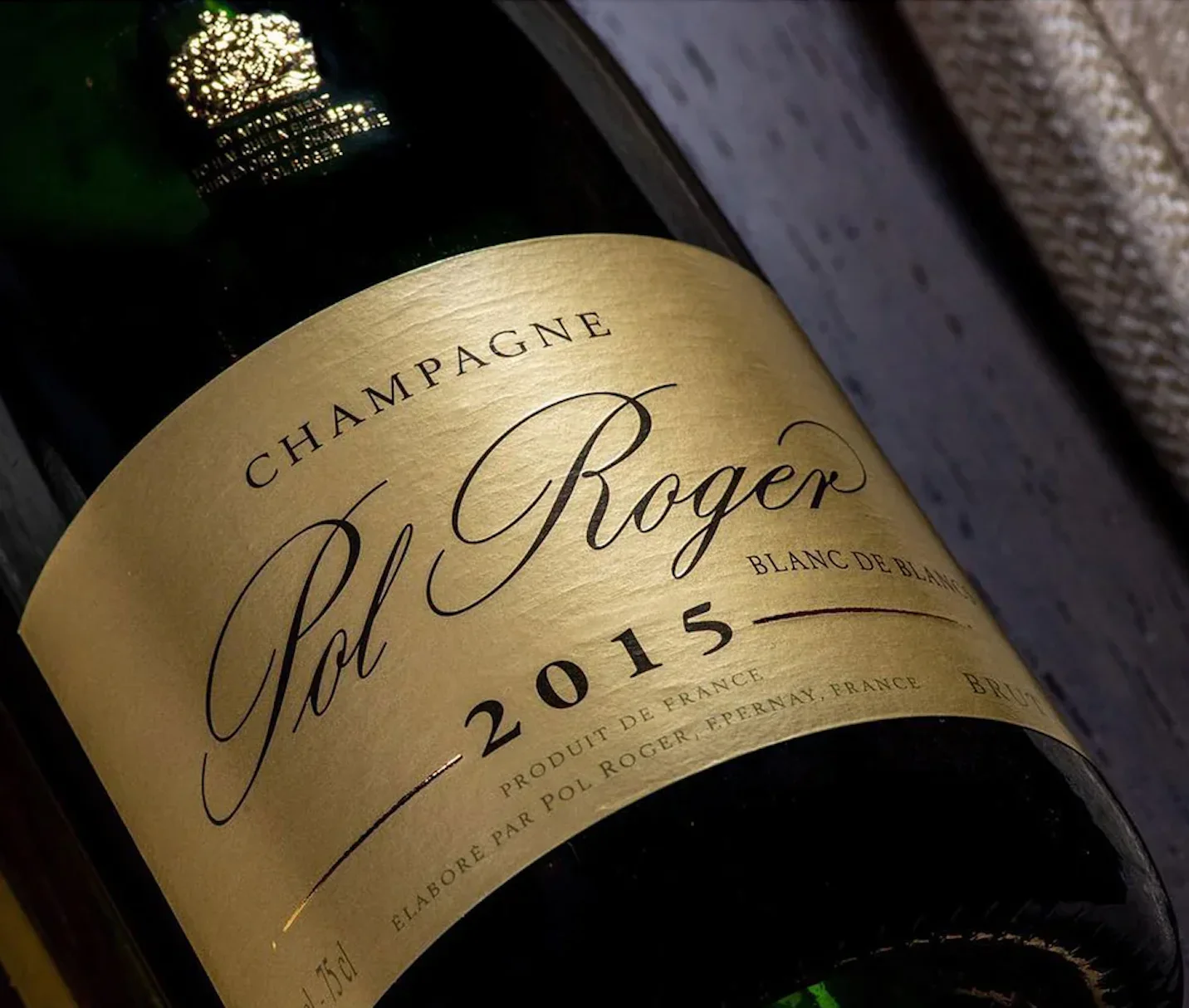Bouteille de champagne Pol Roger, année 2015, avec étiquette dorée, près d’un mur en pierre.