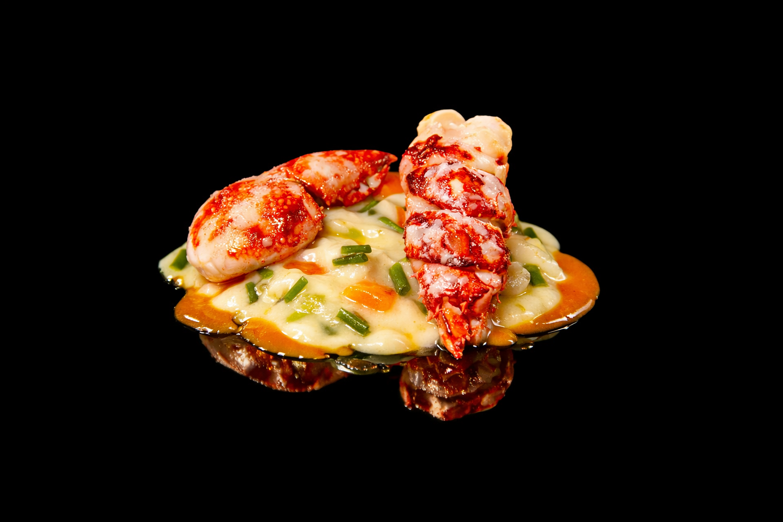 Crevettes et calamars en sauce sur un lit de légumes et de purée, avec des piments rouges