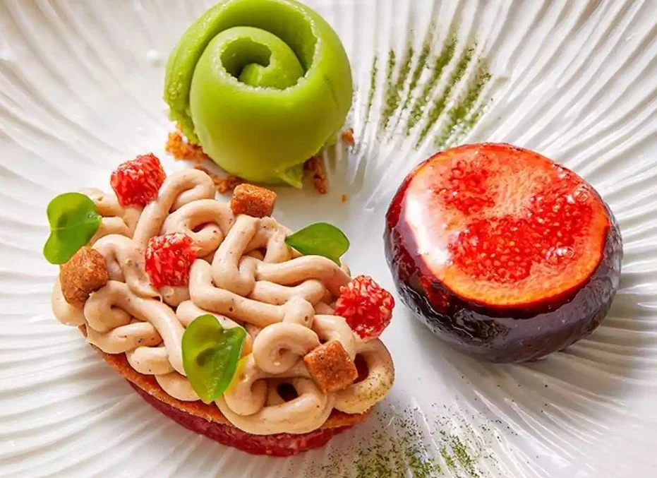 Une assiette avec une tomate, un écheveau spiralé de concombre et une tartine garnie de pâtes, de petits morceaux de tomates, de feuilles de basilic et de croûtons.