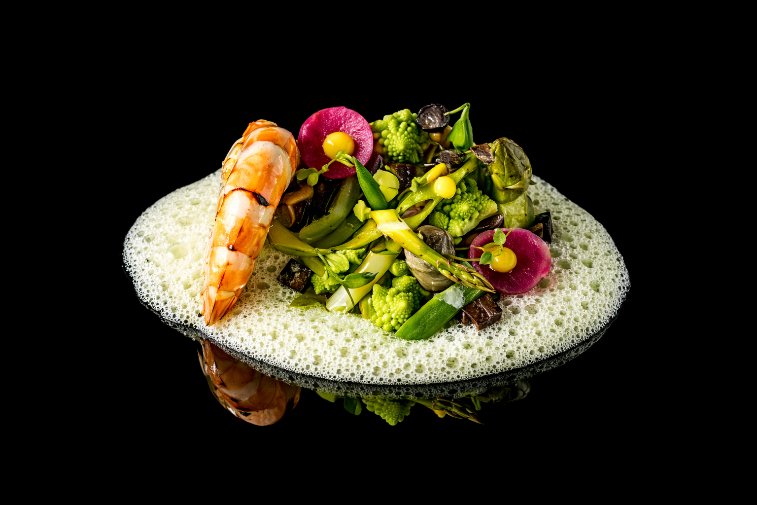 Assiette de légumes verts et fruits avec une crevette sur une mousse blanche, présentation gastronomique.