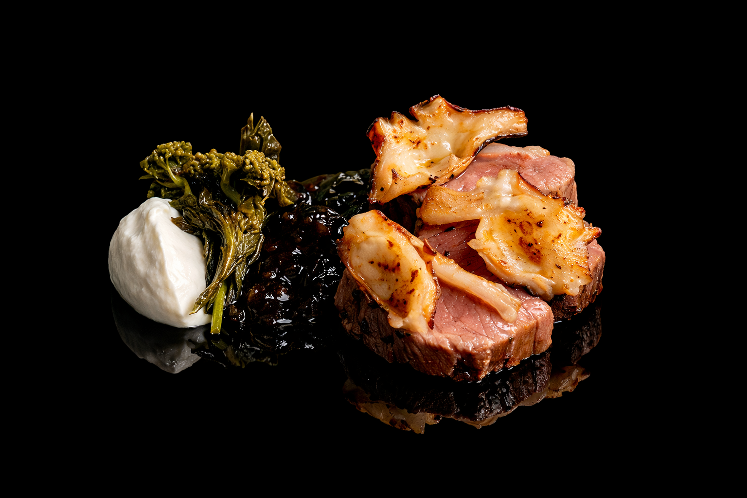 Assiette de viande rouge, sauce béchamel, légumes verts et un trempette blanche sur un fond noir.