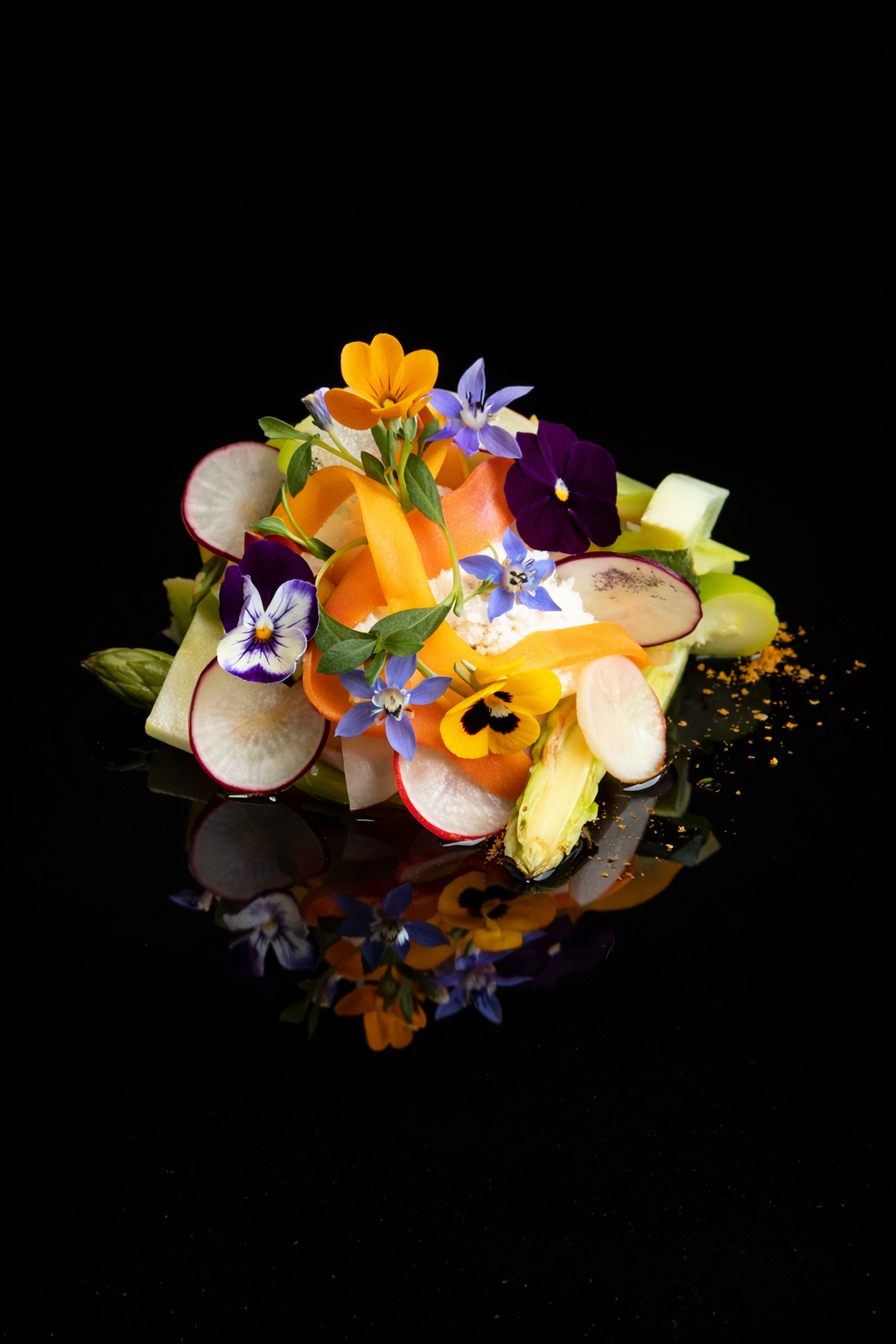 Une salade colorée composée de radis, carottes, concombres, et fleurs comestibles sur fond noir.