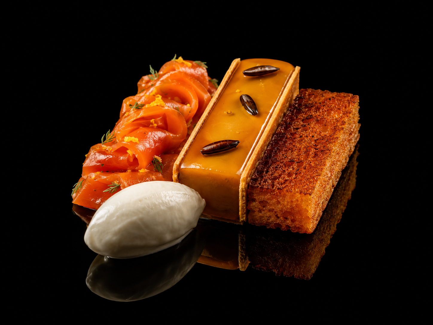 Assiette de tapas avec saumon fumé, une quenelle de crème, une tartelette au caramel décorée de graines, et du pain croustillant, sur fond noir.