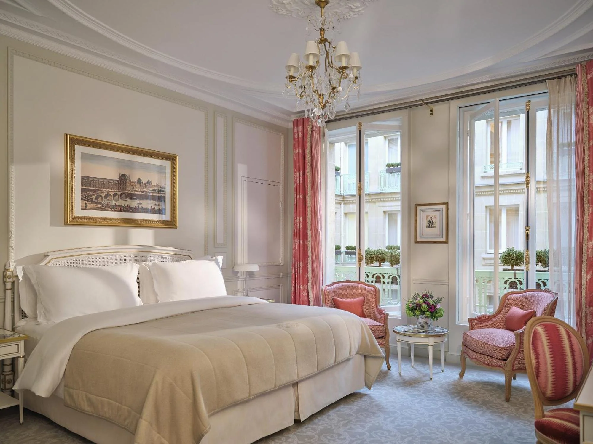 Chambre élégante avec un lit à baldaquin, des fauteuils roses et une vue sur un balcon parisien.