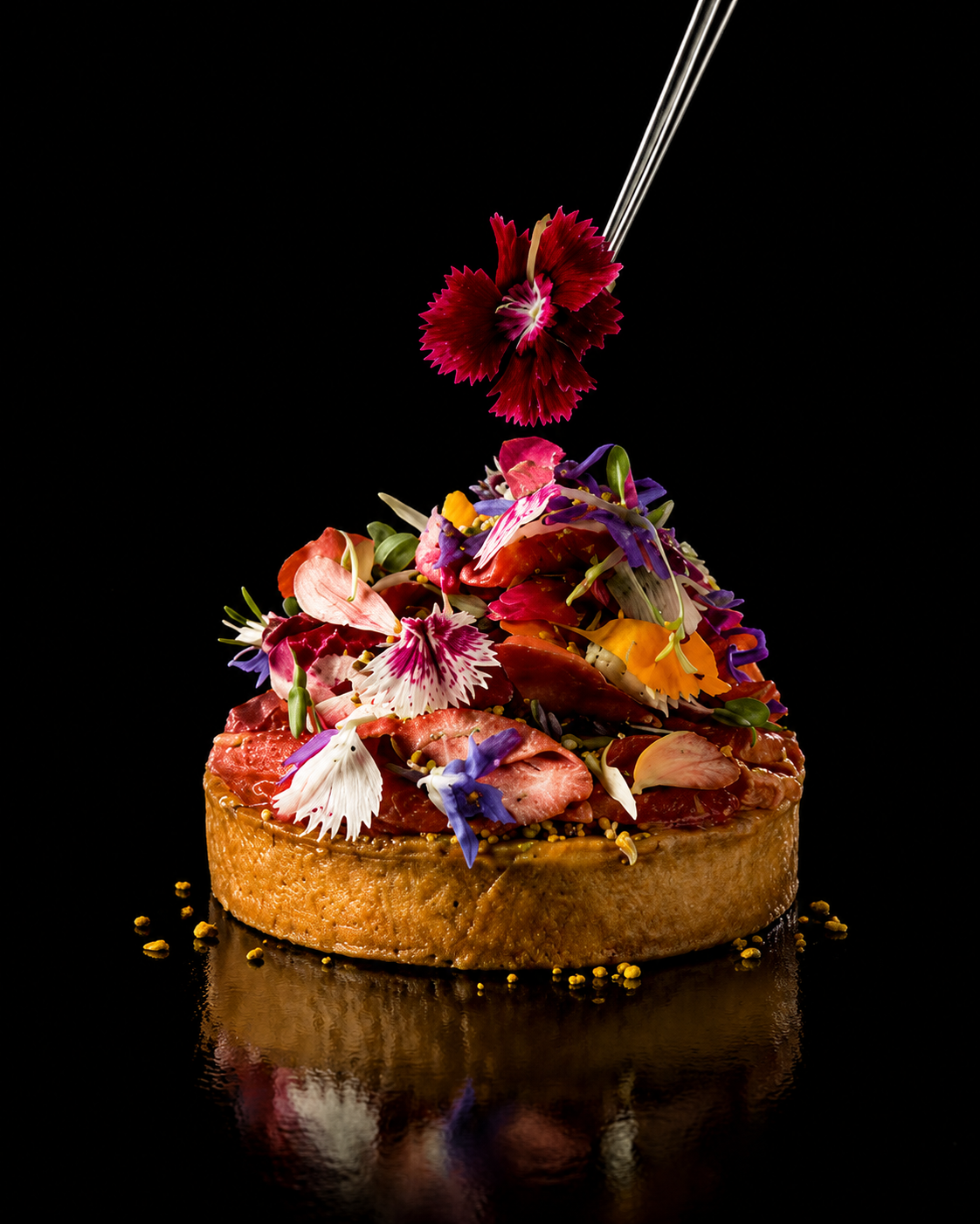 Gâteau décoré avec des fleurs comestibles colorées et une plaque en métal.