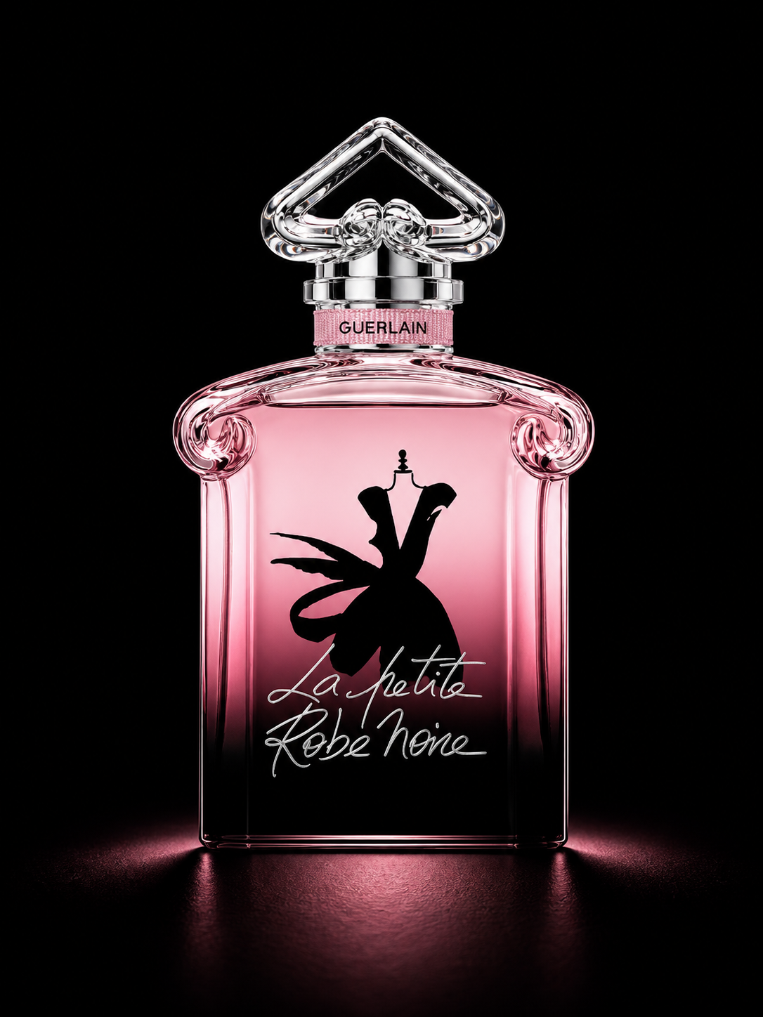Flacon de parfum rose de Guerlain intitulé 'La Petite Robe Noire' avec un bouchon en forme de cœur en cristal, présenté sur un fond noir