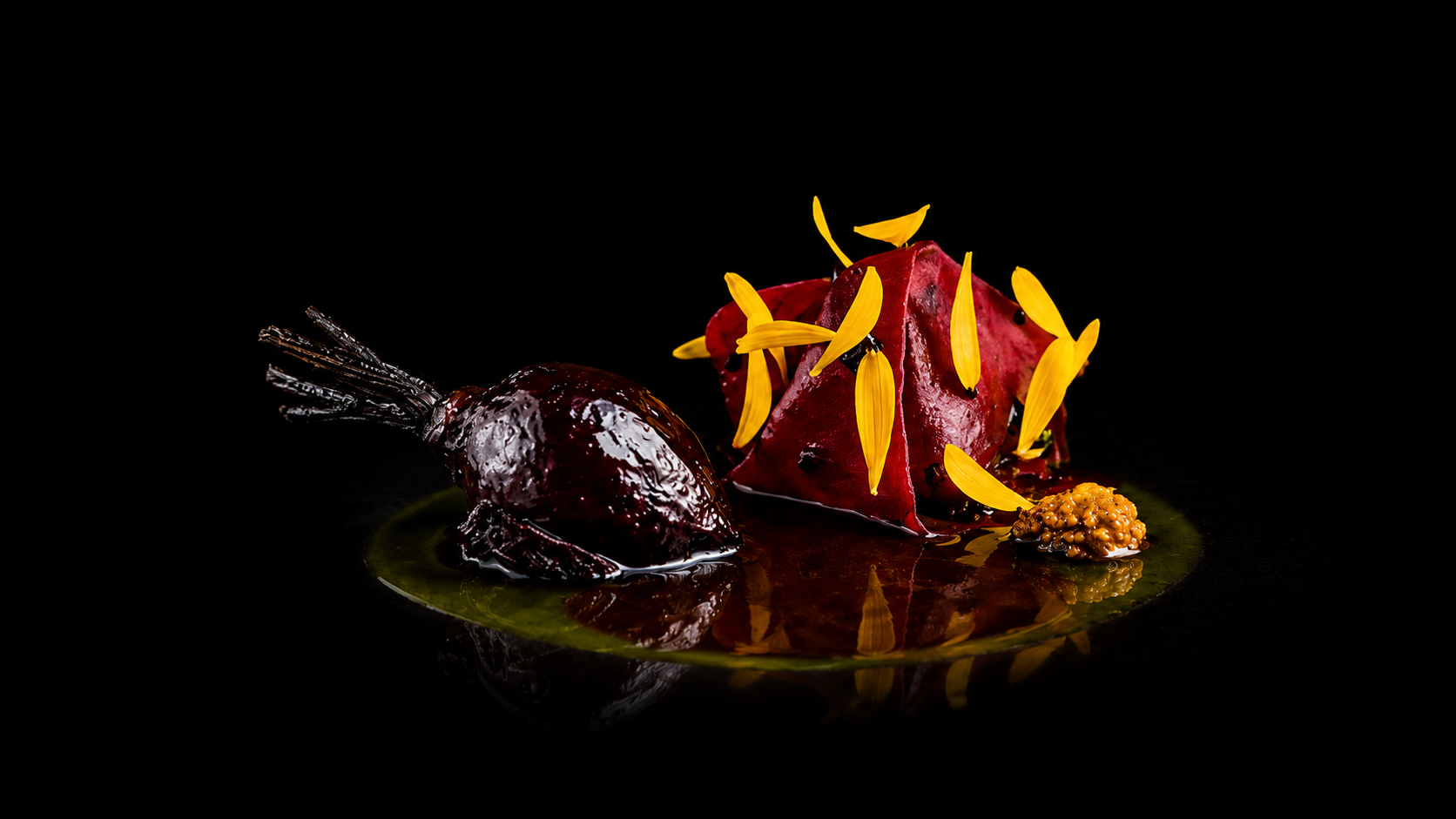 Plat de cuisine sophistiquée avec une pièce de viande glacée, garnitures colorées, et décor floral sur fond noir