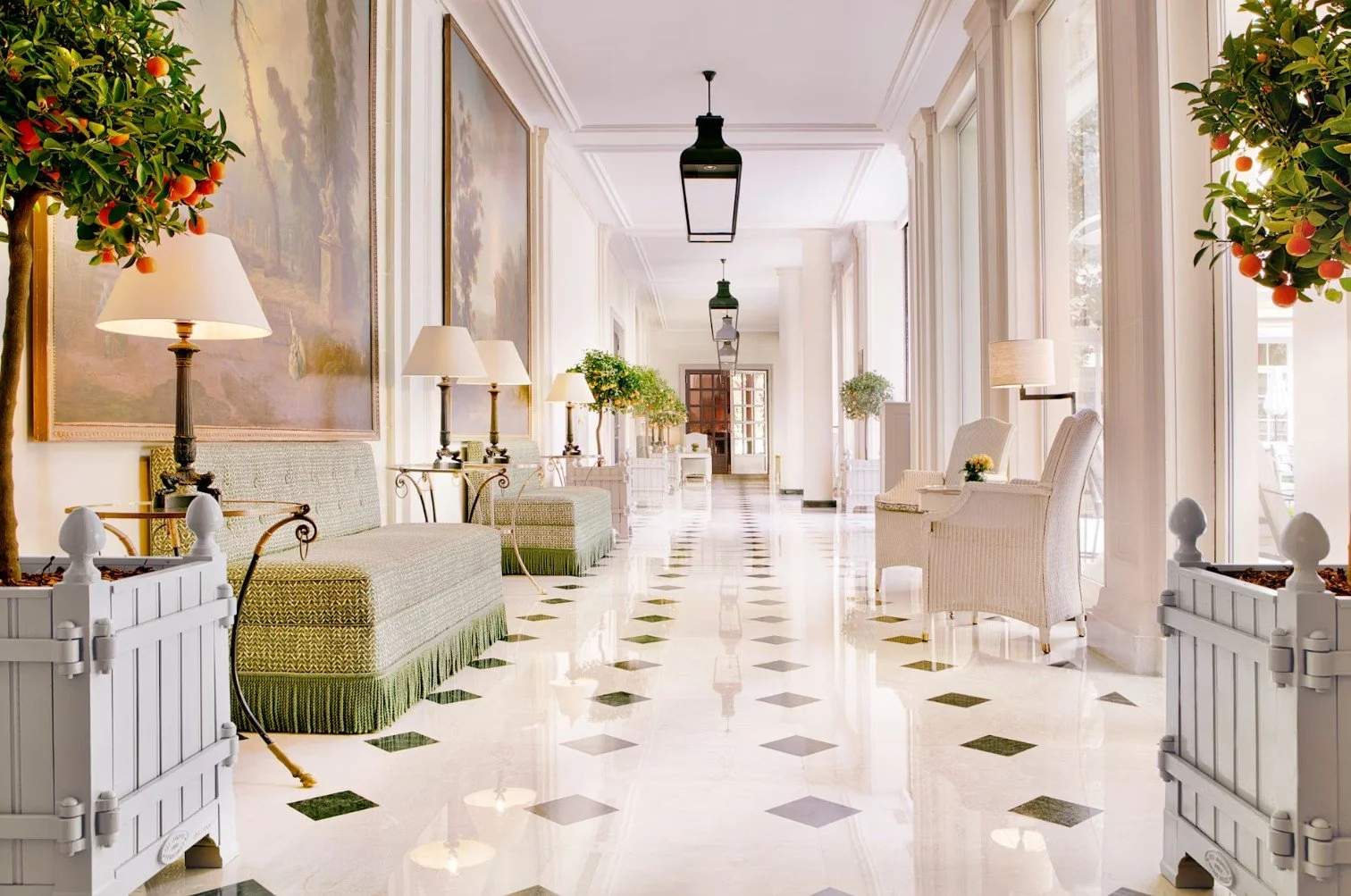 Hall d'entrée élégant avec sofas, lampes, plantes, et grandes fenêtres lumineuses dans un style classique chic.