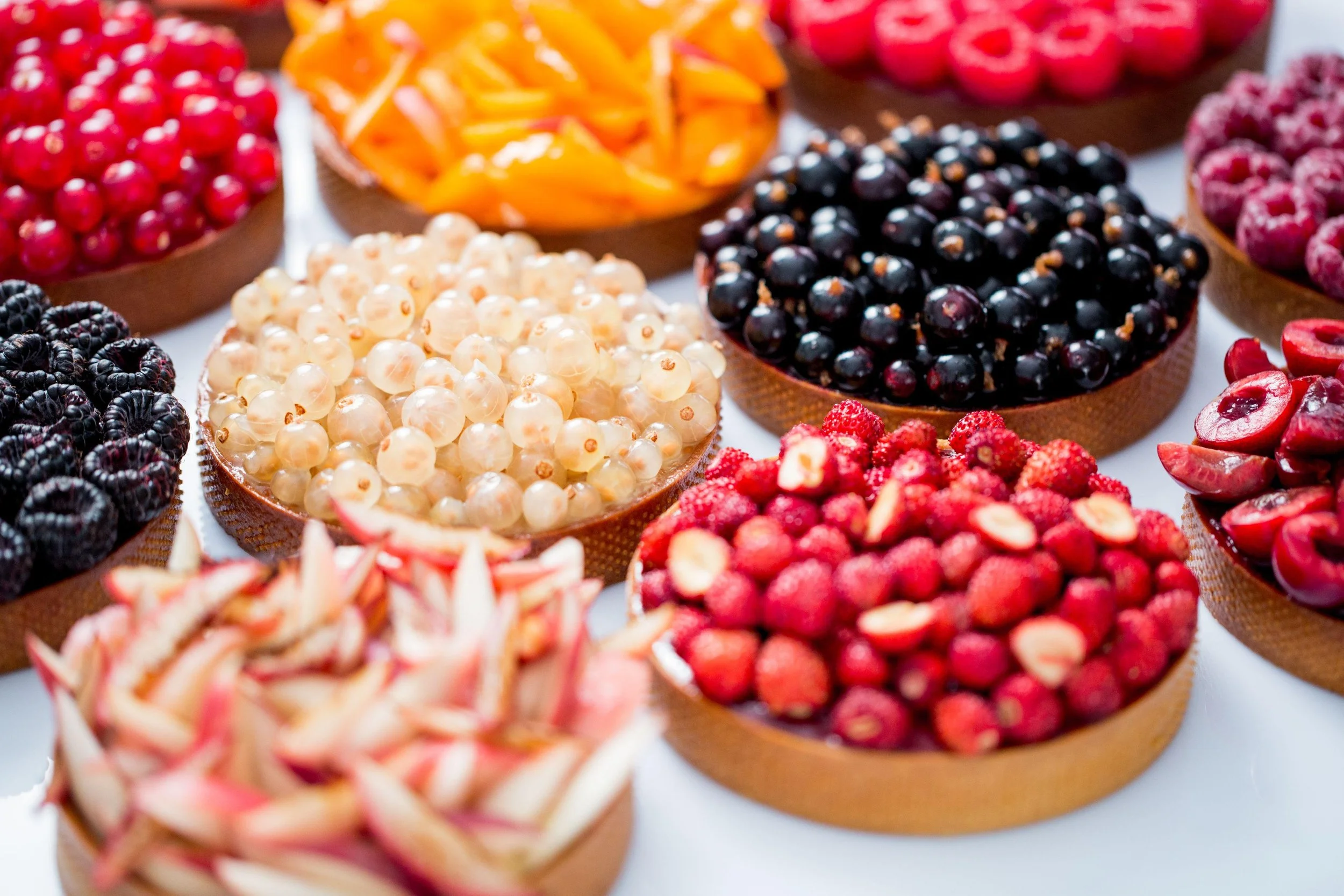 Assortiment de fruits rouges et fruits découpés dans des paniers en bois.