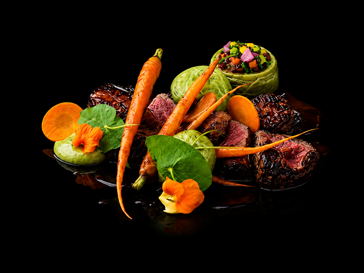 Viande rouge cuite, carottes, petits pois, feuilles de shiso, fleurs d'hibiscus, et légumes décoratifs sur un fond noir.