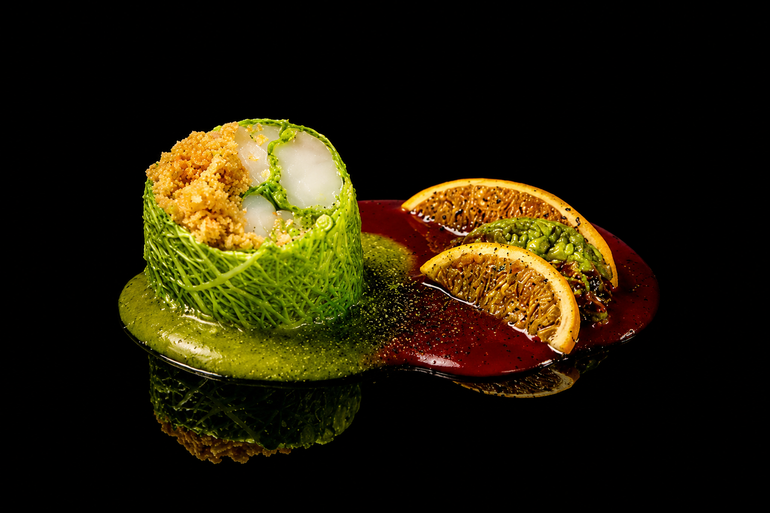 Plat gastronomique élégant avec un rouleau en cage de nacelle en pâte verte, rempli de quinoa et légumes, accompagné de tranches d'orange et de citron, garnissant une sauce rouge et verte contre un fond noir.