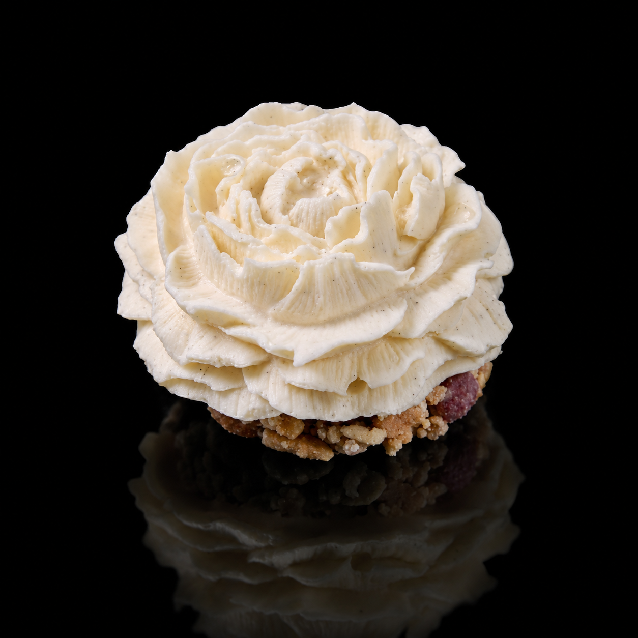 Cupcake avec de la crème en forme de roses blanches sur un fond noir.