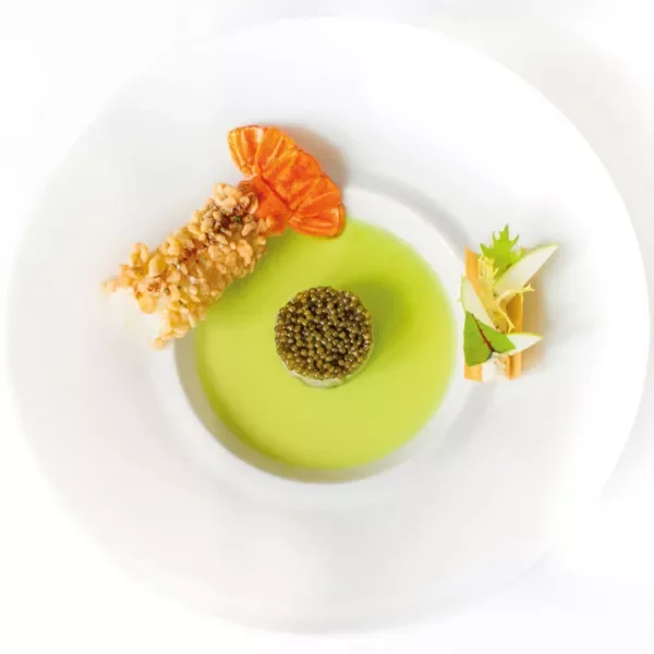 Assiette d'apéritif avec un boudin noir en gelée, un tartare de caviar d'été, une crevette tempura, et une garniture verdoyante aux légumes.