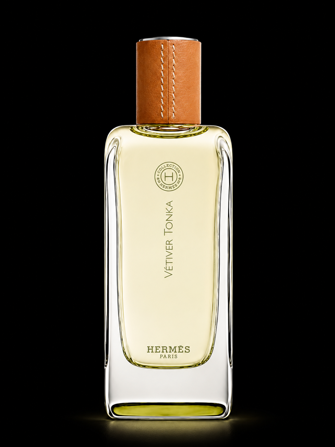 Flacon de parfum Hermès 'Vétiver Tonka' avec un bouchon en cuir et une étiquette dorée, sur fond noir
