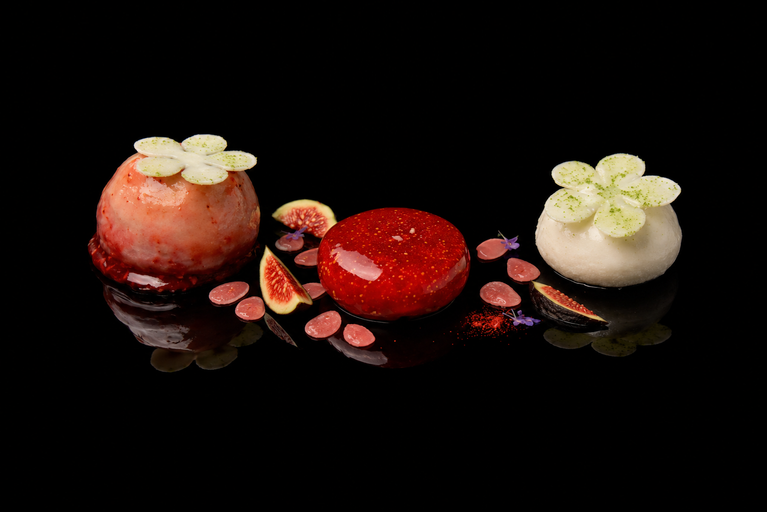 Gâteaux en forme de fruits avec des décorations florales sur fond noir.
