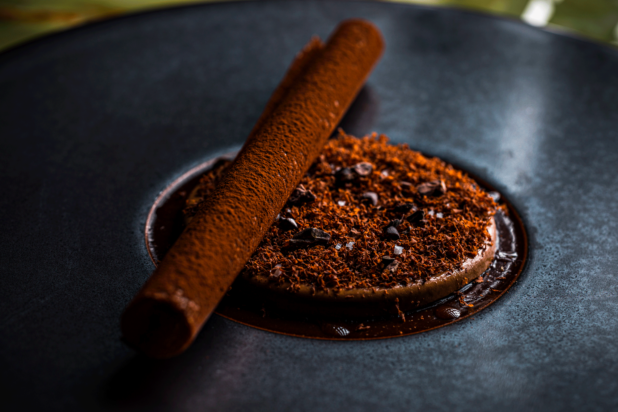 Gâteau au chocolat avec une cannelle en bâton sur un plat noir.