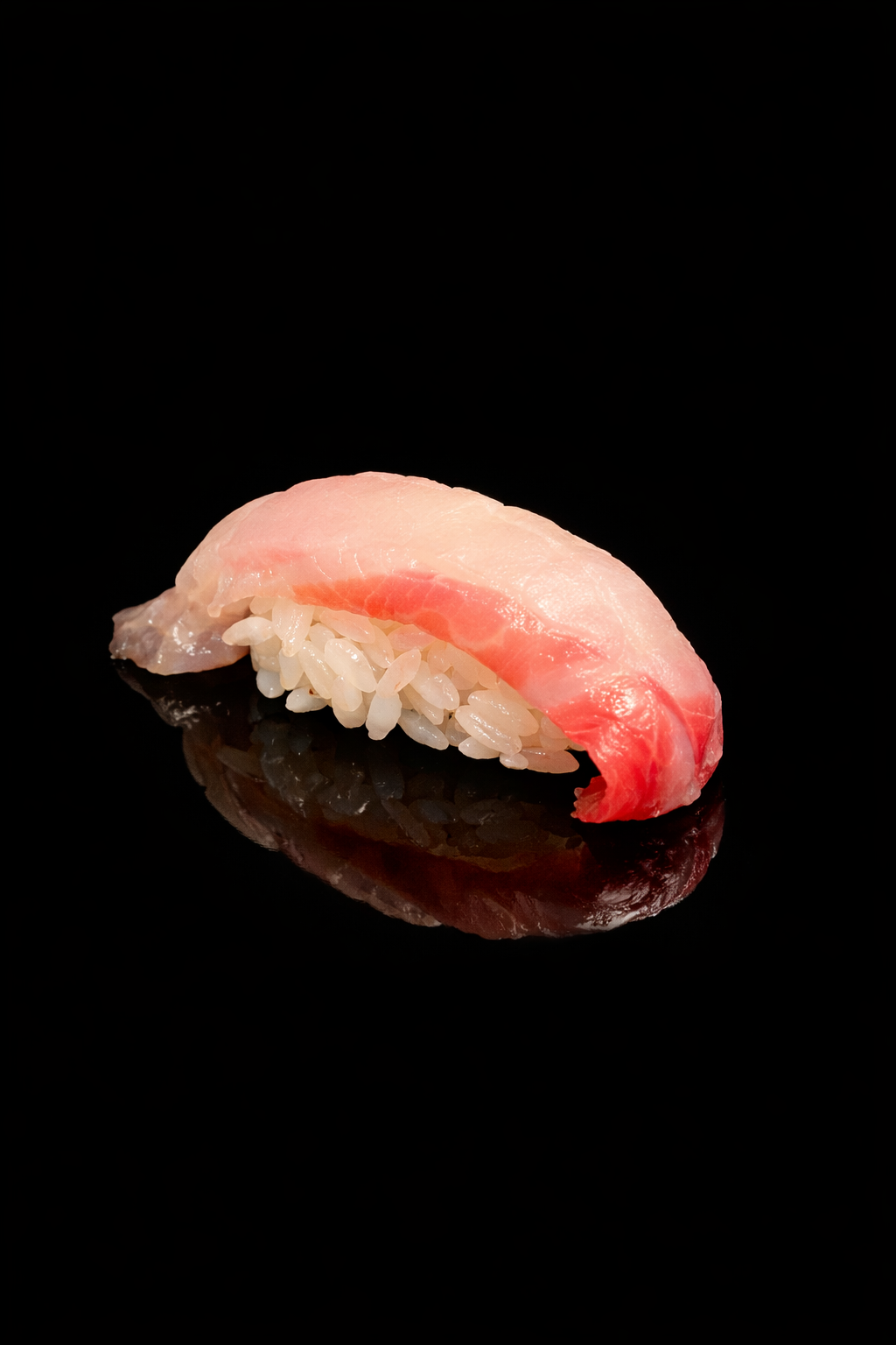 Sushi de poisson cru sur un fond noir, avec riz blanc en dessous.
