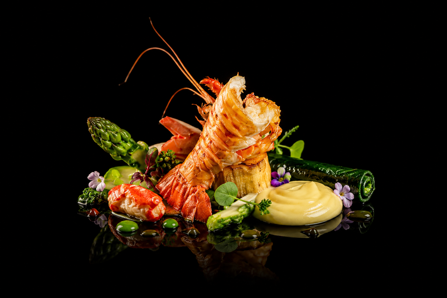 Assiette de fruits de mer avec crevettes, asperges, sauces, fleurs comestibles sur fond noir.