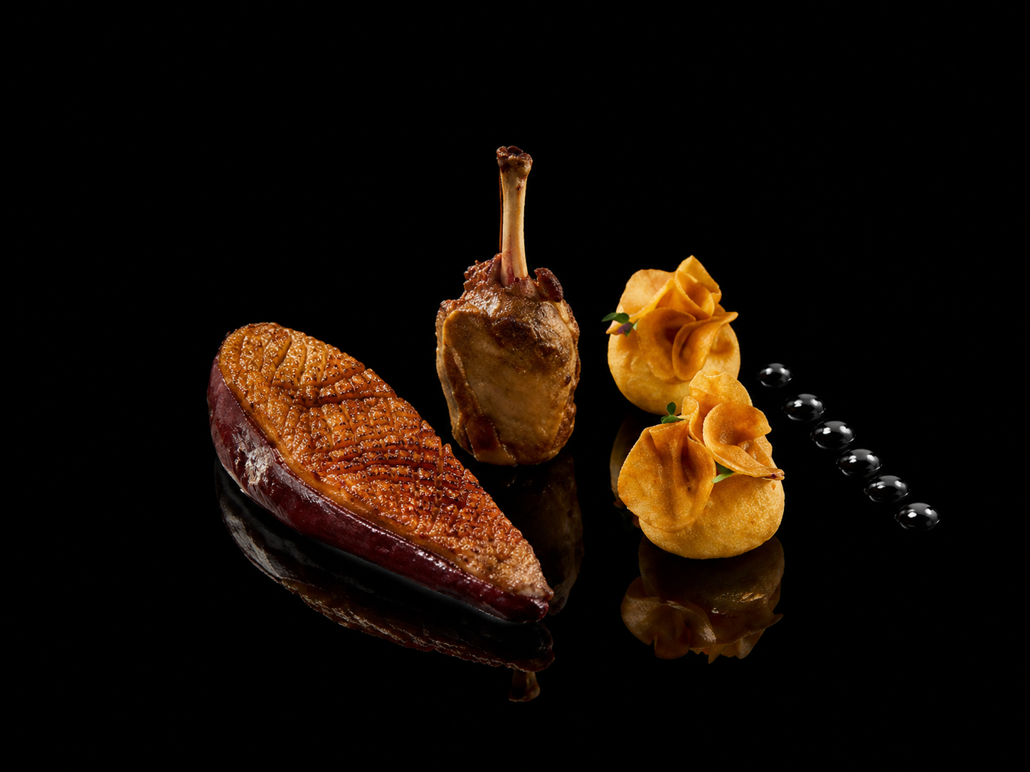 Assiette de fine cuisine avec une tranche de patate douce rôtie, un carré de foie gras avec une queue de canard, deux quenelles de purée garnies de microgreens, et une ligne de perles de sauce noire.