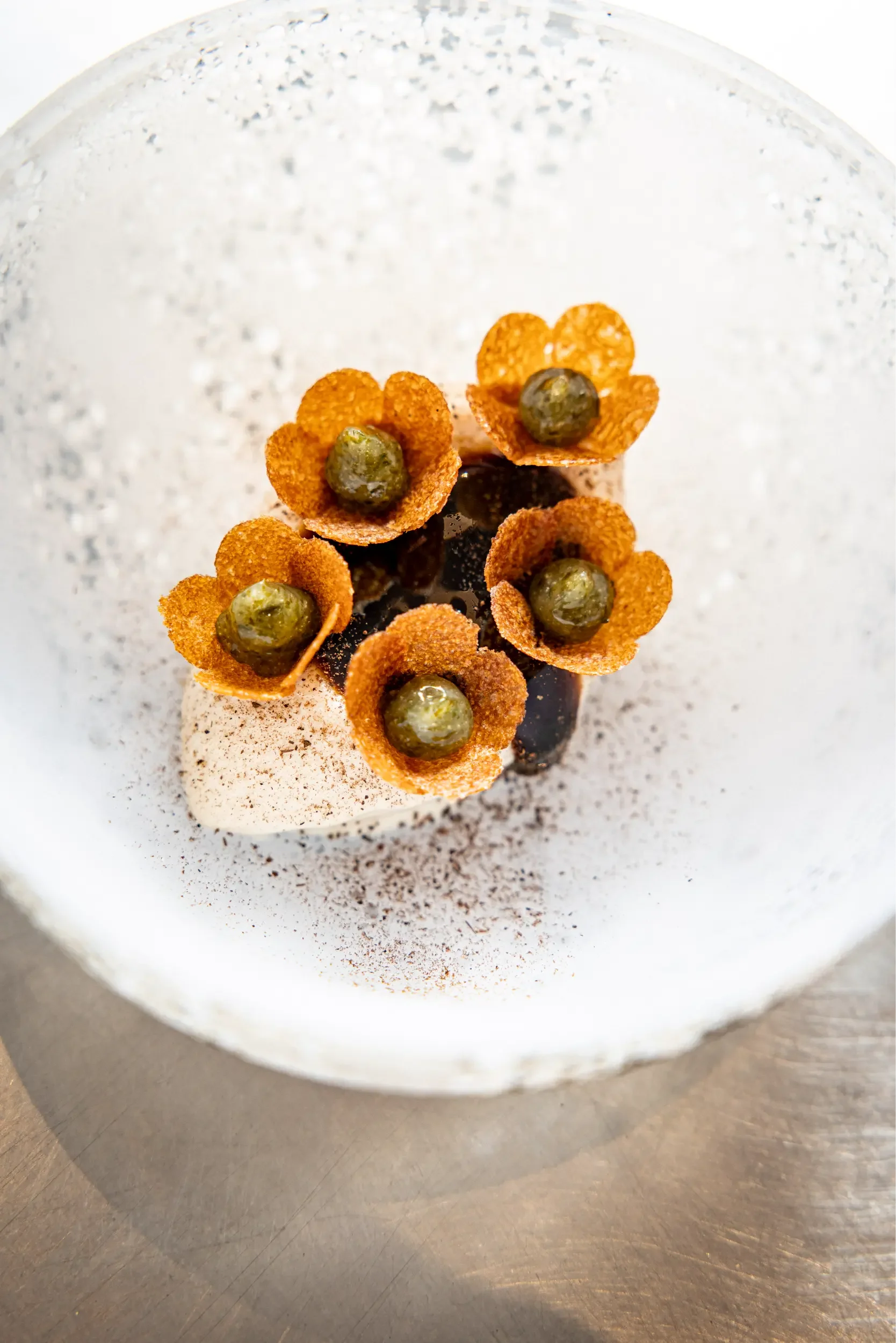 Gâteau décoré avec cinq fleurs de cornflakes avec un brin d’herbe au centre, présentation élégante en assiette