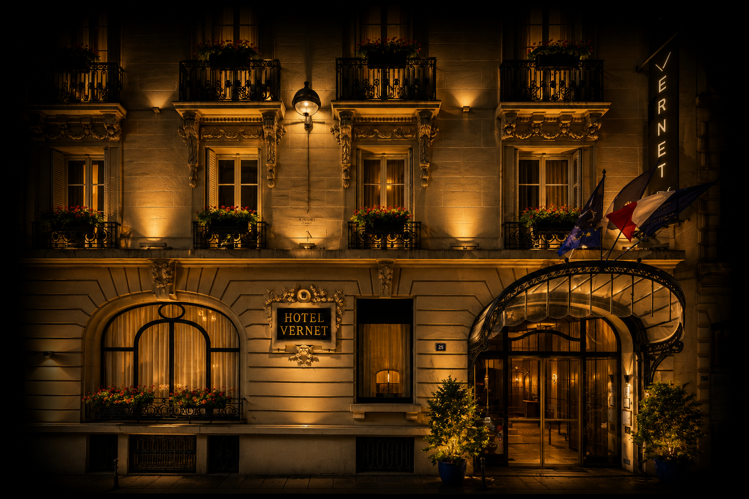 Façade illuminée d'un hôtel parisien appelé Hôtel Vernet, avec fenêtres à balustrades en fer forgé, drapeaux français, européens et autres, et porte d'entrée en verre, la nuit.