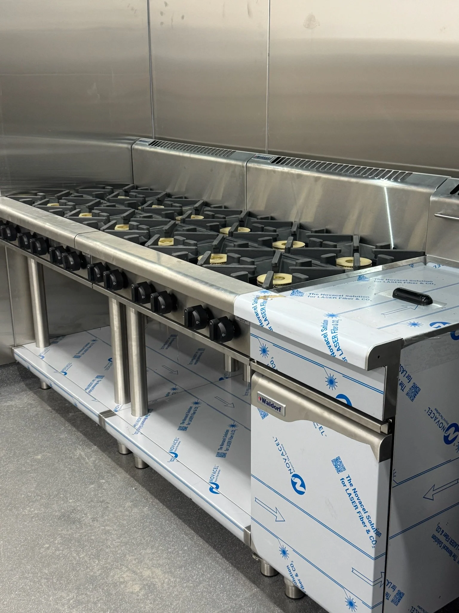 Stainless steel commercial stove with multiple burners in a kitchen setting