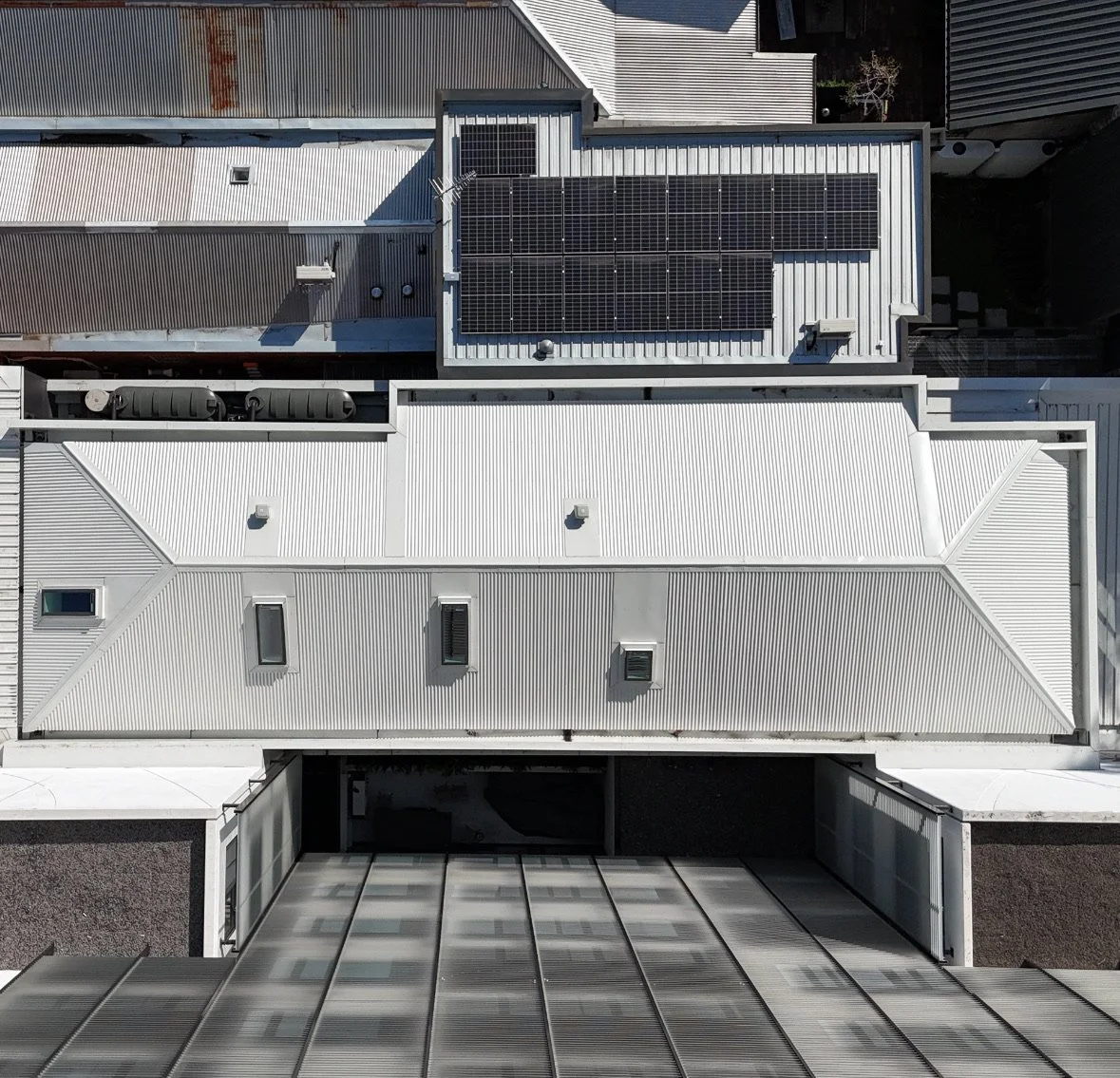Bird's eye view of rooftops with solar panels installed on some buildings.