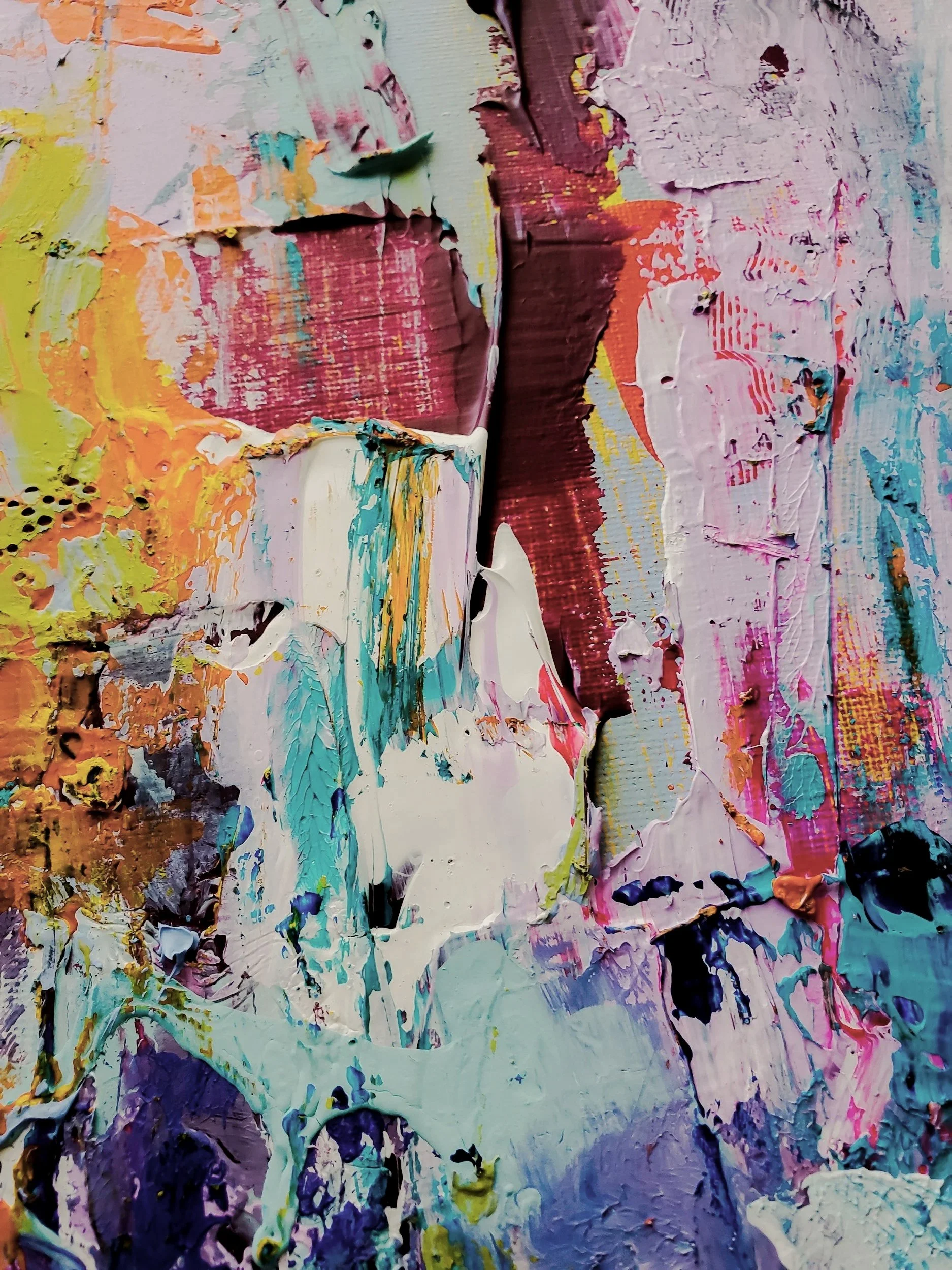 Close-up of an abstract textured painting with thick layers of colorful paint including yellow, pink, purple, white, and blue, with visible brushstrokes and palette knife marks.