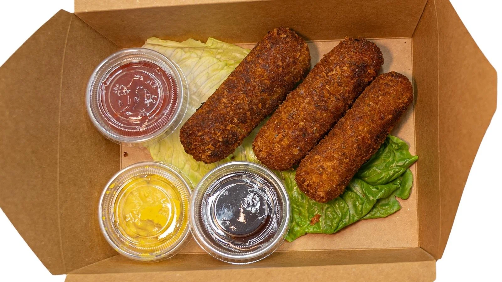 Three deep-fried croquettes on lettuce with three small containers of dips—ketchup, mustard, and soy sauce—in a brown cardboard box.