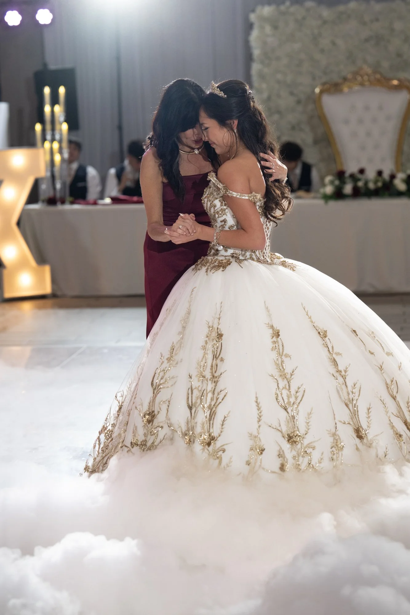 An intimate and emotional dance shared between Alex and her mother. Surrounded by soft candlelight and low-lying fog, the moment feels cinematic and heartfelt. The closeness, gentle smiles, and embrace reflect the deep bond and meaning behind this Qu