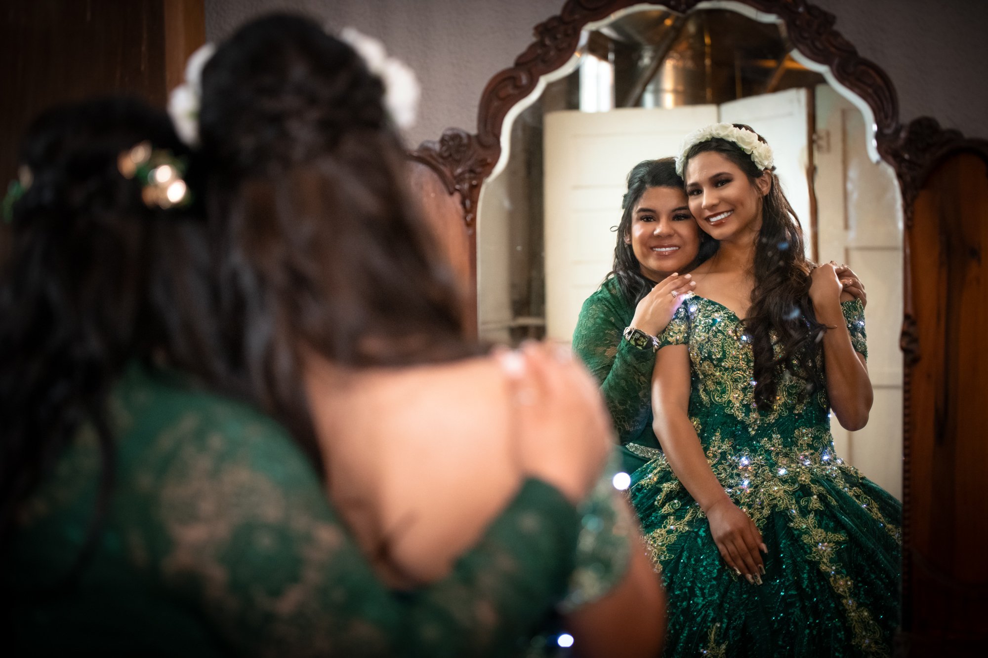 Standing before an antique mirror, Natalie smiles as her mother wraps her arms around her. Their reflection captures more than beauty, it captures pride, gratitude, and a moment they’ll both carry forever.