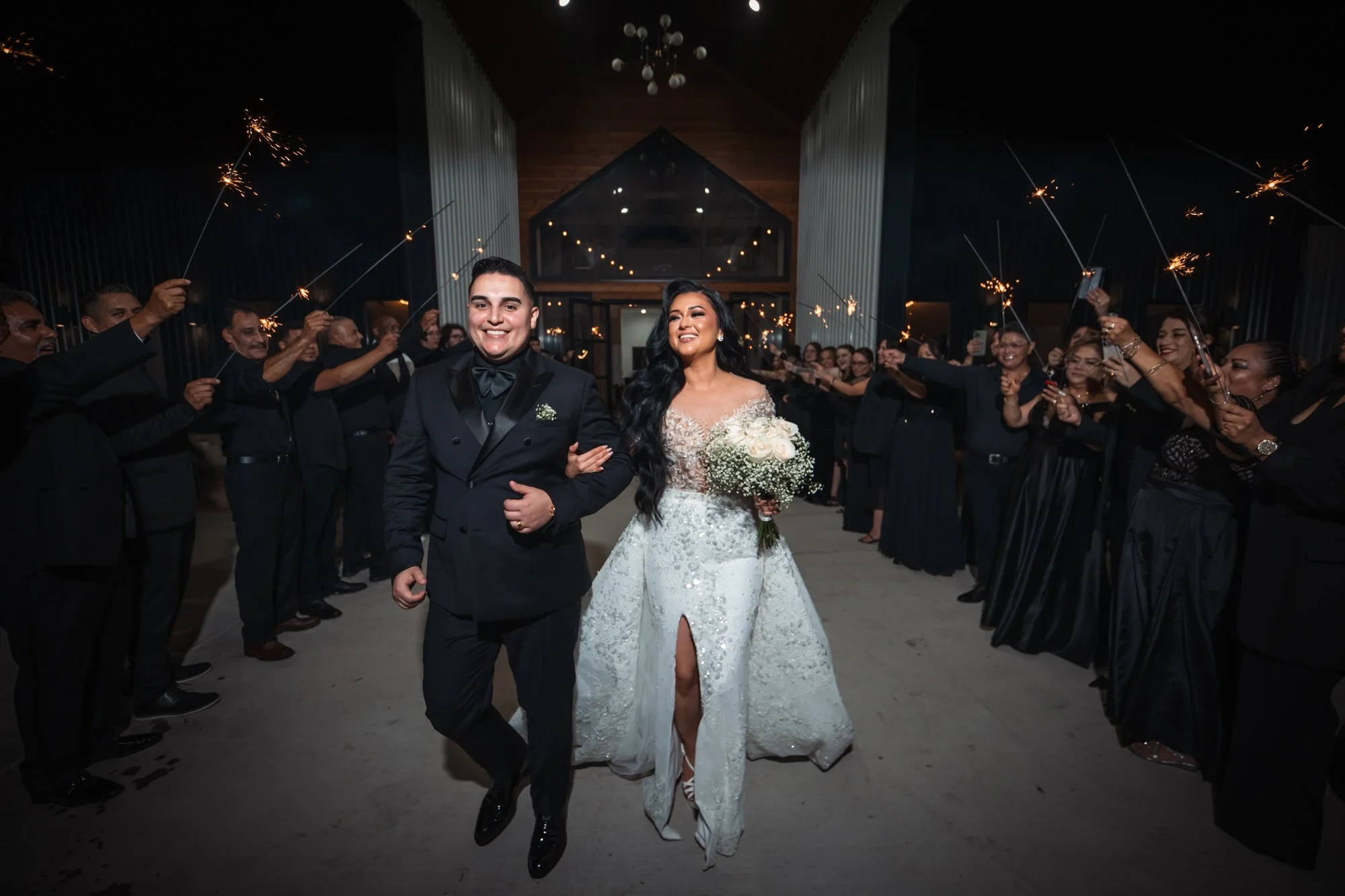 Surrounded by sparklers and cheering loved ones, the bride and groom make their grand nighttime exit, celebrating the beginning of their marriage in a cinematic send-off.