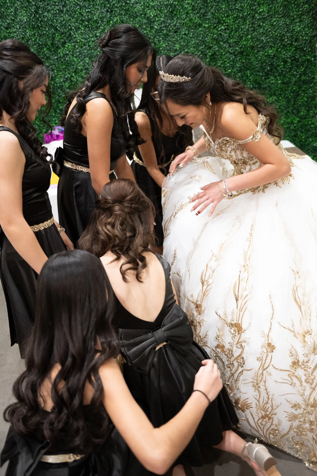 A behind-the-scenes moment as Alex is surrounded by her court in matching black dresses. They adjust her gown and prepare for the next part of the celebration, highlighting the friendship, support, and sisterhood that make a Quinceañera truly special