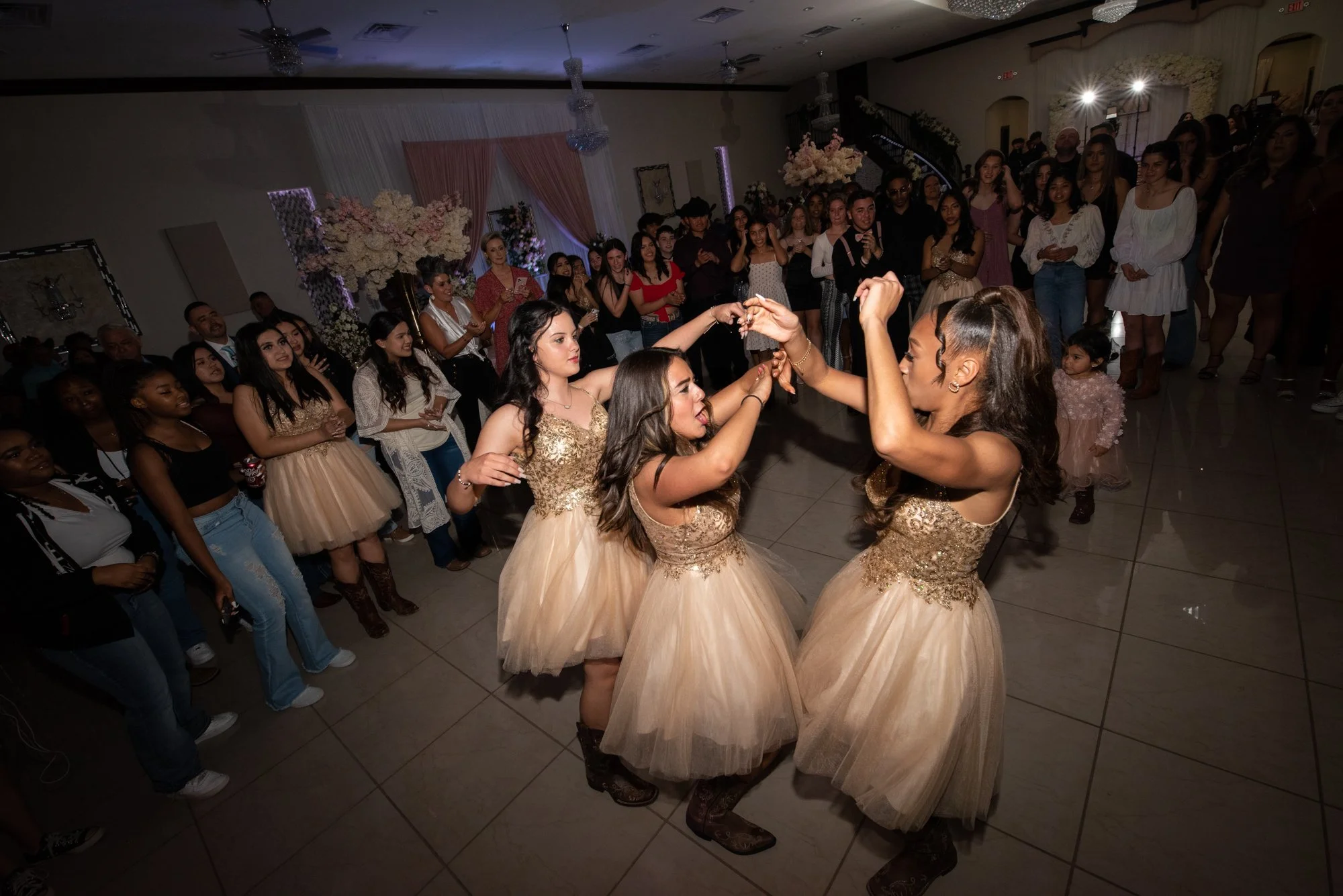 The quince court takes the floor in matching champagne dresses and cowboy boots, beginning their choreographed dance routine. Surrounded by family and friends, this high-energy performance showcases confidence, teamwork, and months of preparation.