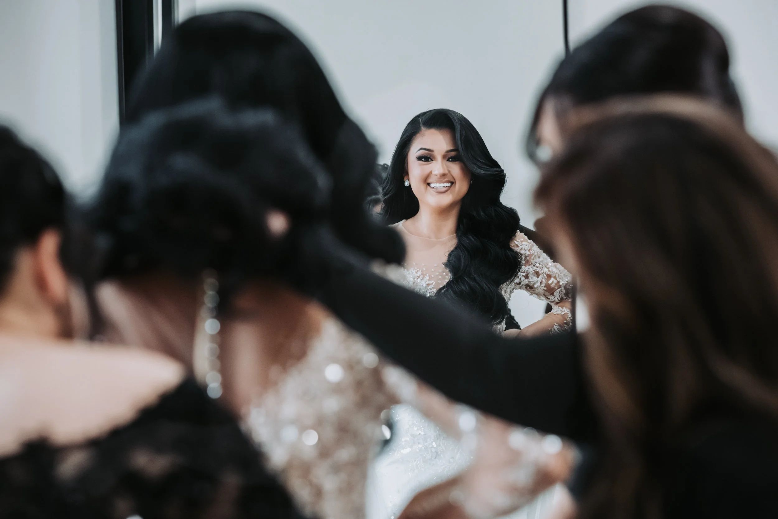 The bride smiles with confidence as she sees herself fully dressed, a powerful reflection of joy, beauty, and readiness before walking down the aisle.