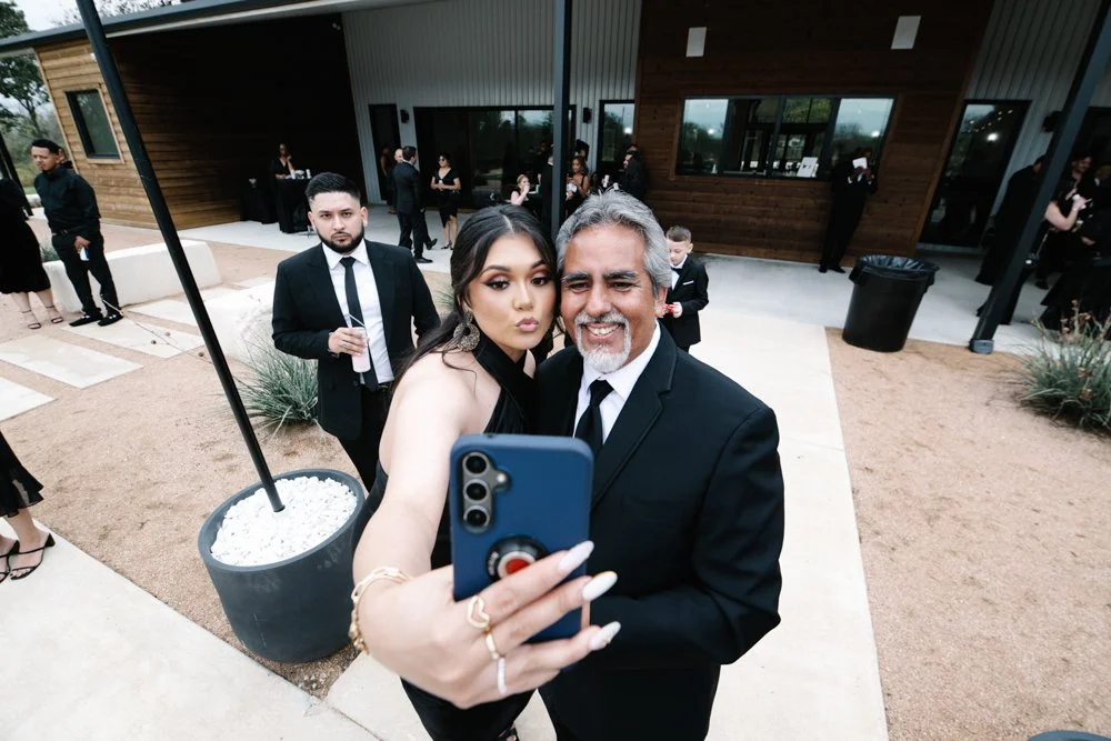 Bride taking a selfie with her father during wedding celebrations at a modern Texas wedding venue.