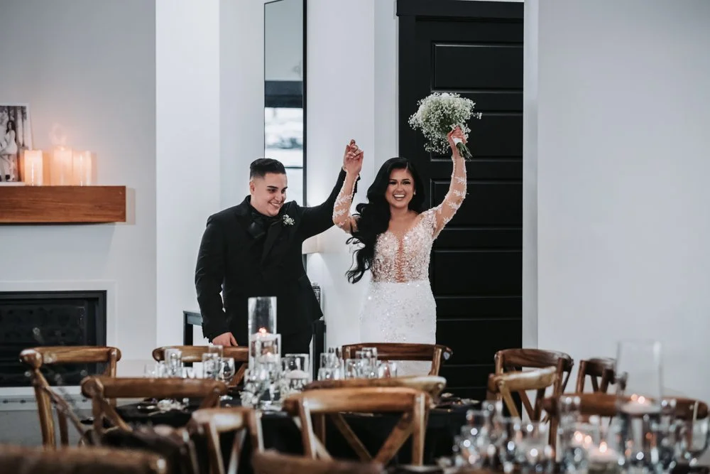 Karen and Matthew make their grand entrance into their wedding reception with joyful smiles as guests welcome them to begin the evening celebration.