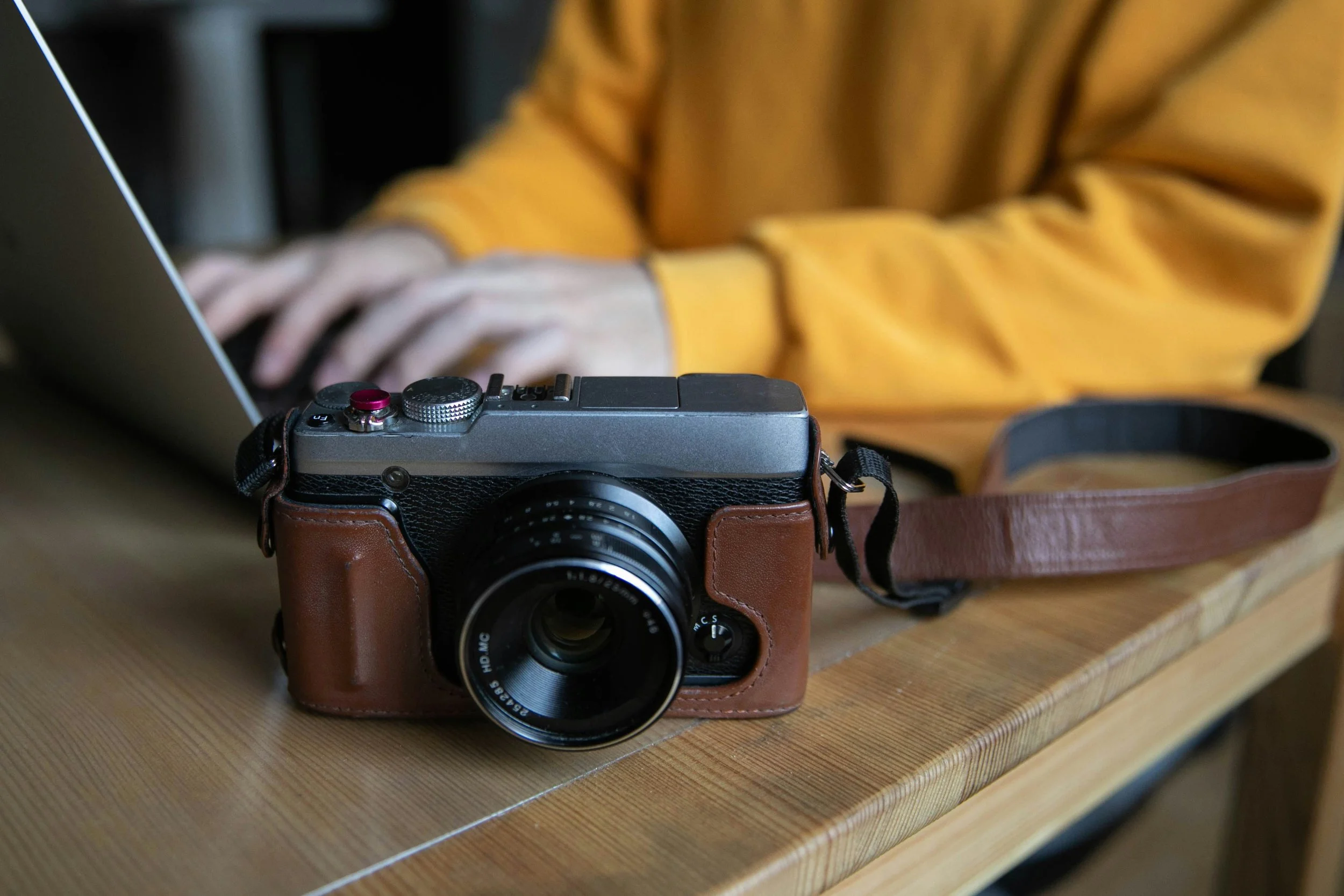 Camera resting on a table beside a laptop, symbolizing planning ahead and booking a professional quinceañera photographer in advance.