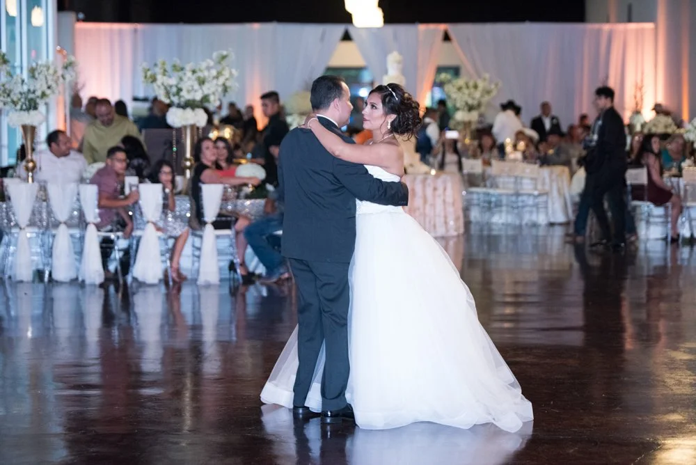 Bride and groom sharing their first dance during an elegant wedding reception surrounded by family and guests.