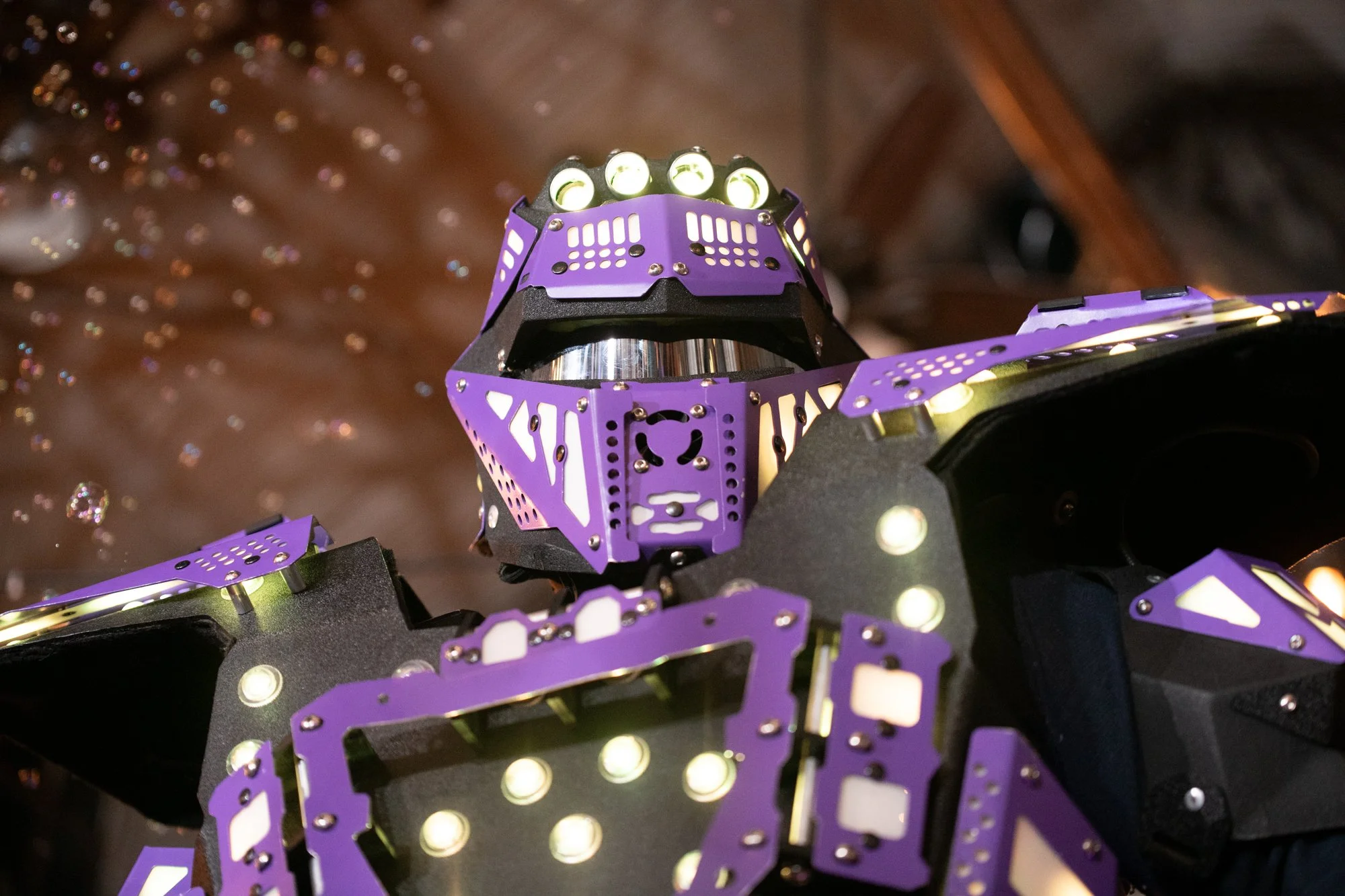 A dramatic close-up of a LED-lit robot entertainer adds a futuristic vibe to the celebration. The lighting contrasts beautifully with the venue’s warm tones, giving the reception a modern entertainment twist.