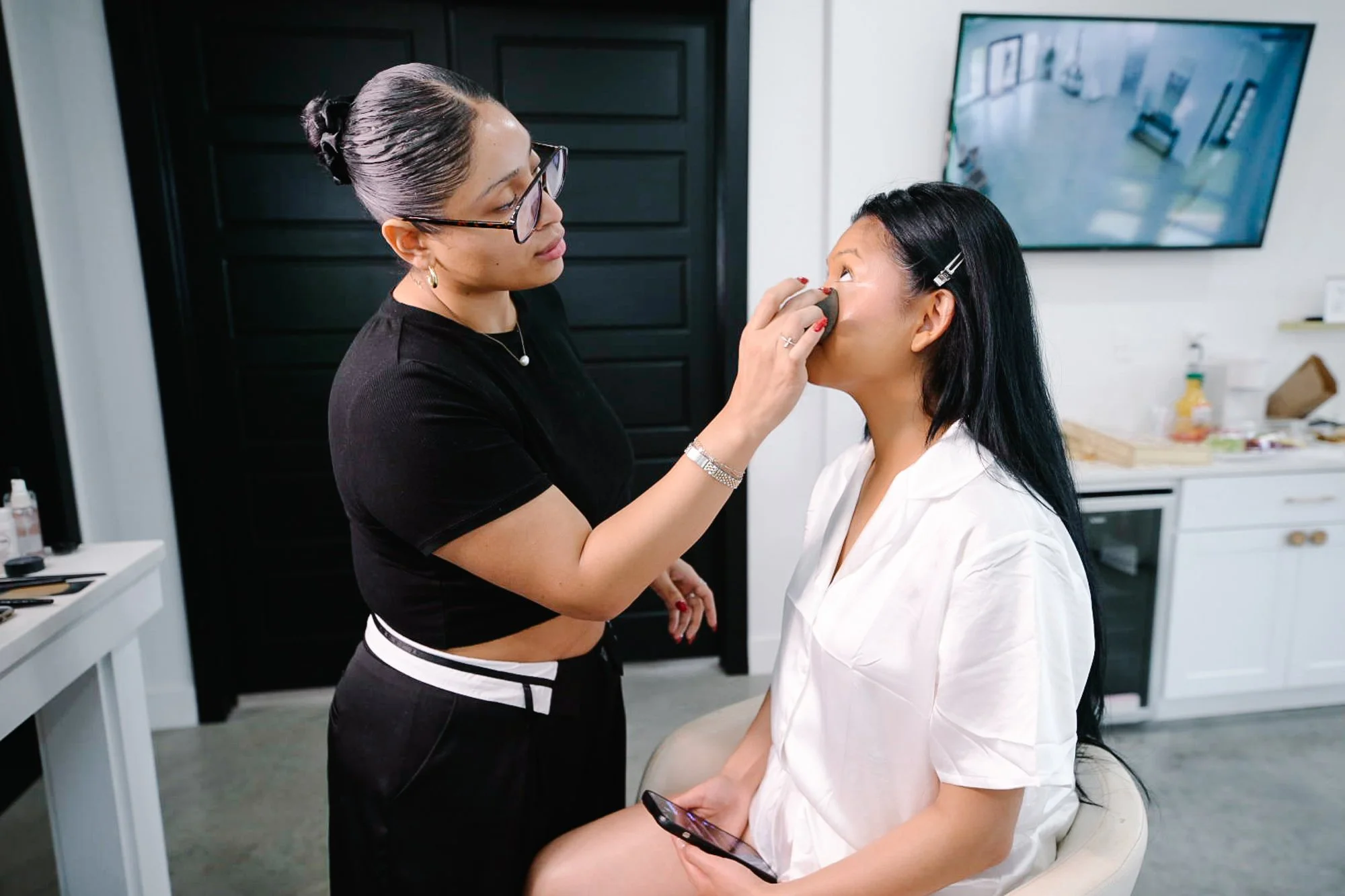 A quiet, intimate moment as the bride has her makeup professionally applied, capturing the calm anticipation and care that begins the wedding day.