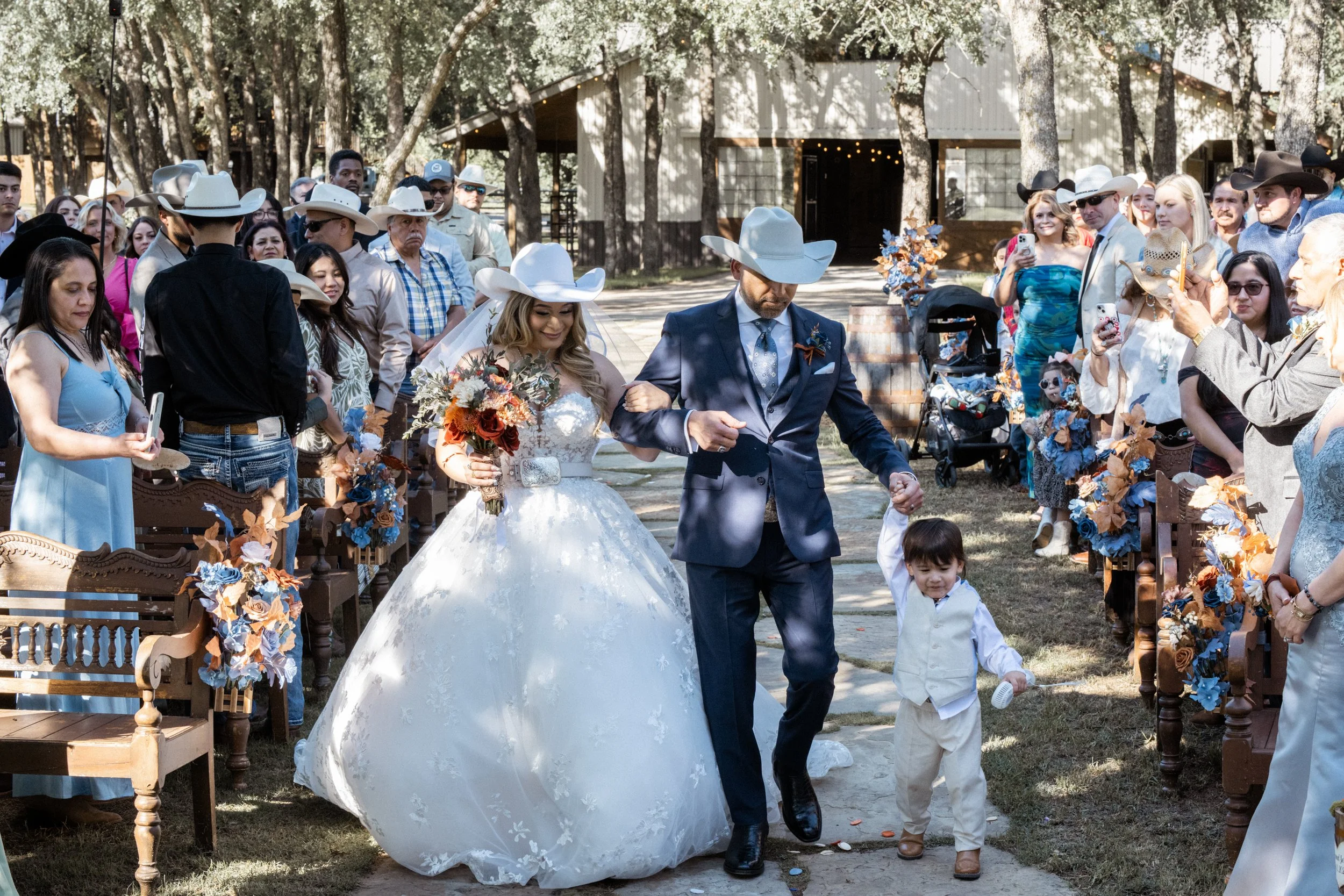 Outdoor wedding ceremony bride walking down aisle with father and child family moment