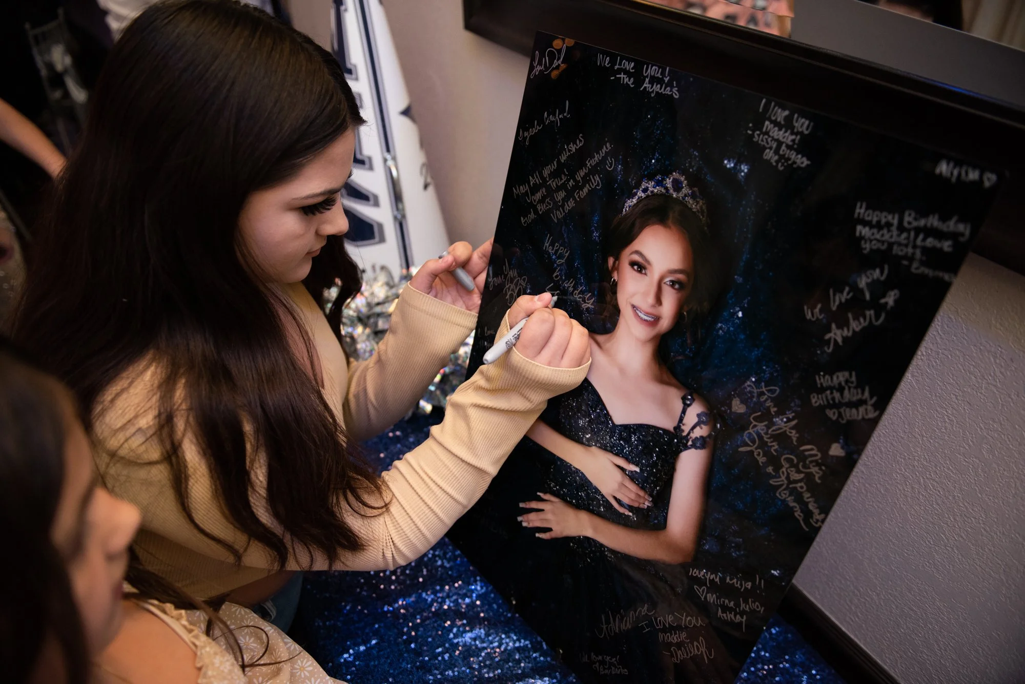 Quinceañera guest signing portrait guestbook with messages at celebration