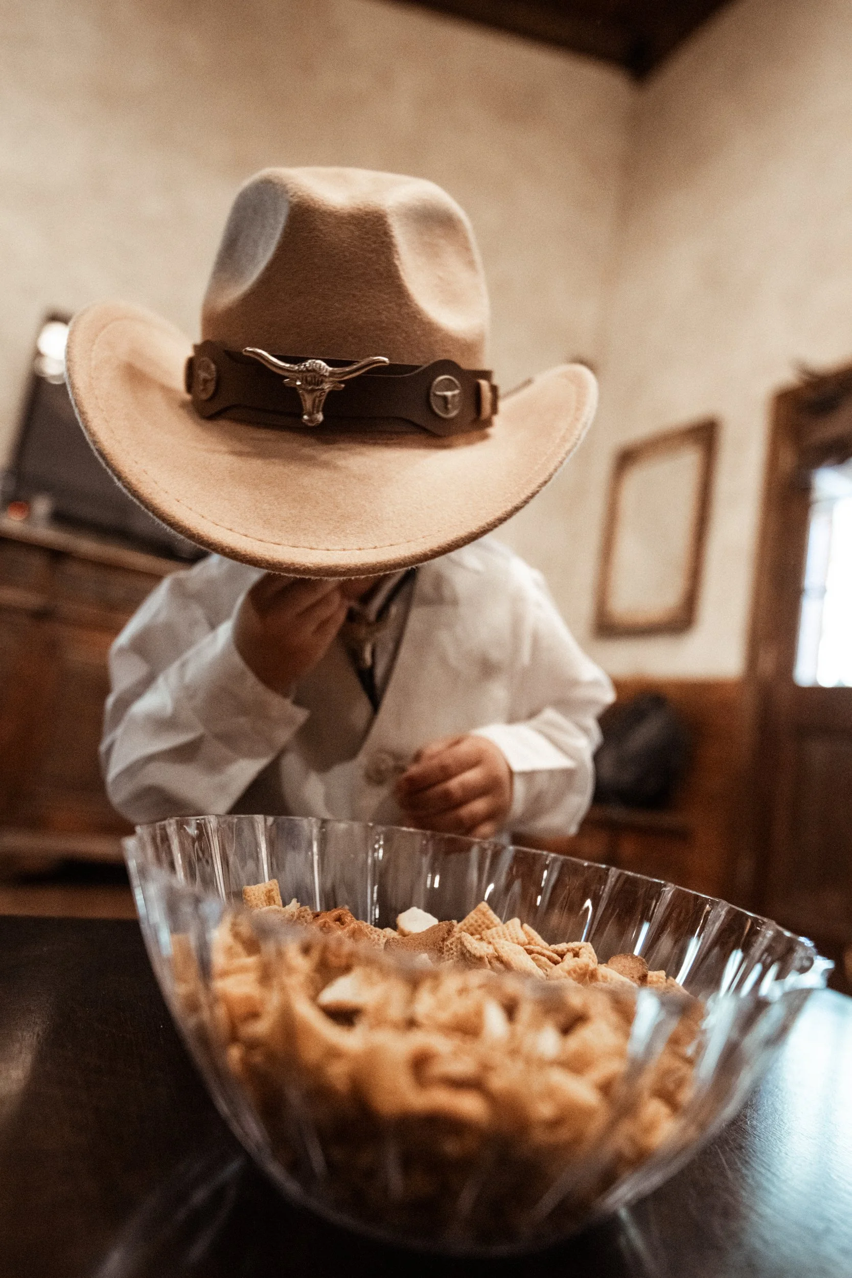 A candid and heartfelt moment featuring a young child wearing a cowboy hat during the wedding day, adding charm, personality, and emotional storytelling to the gallery.