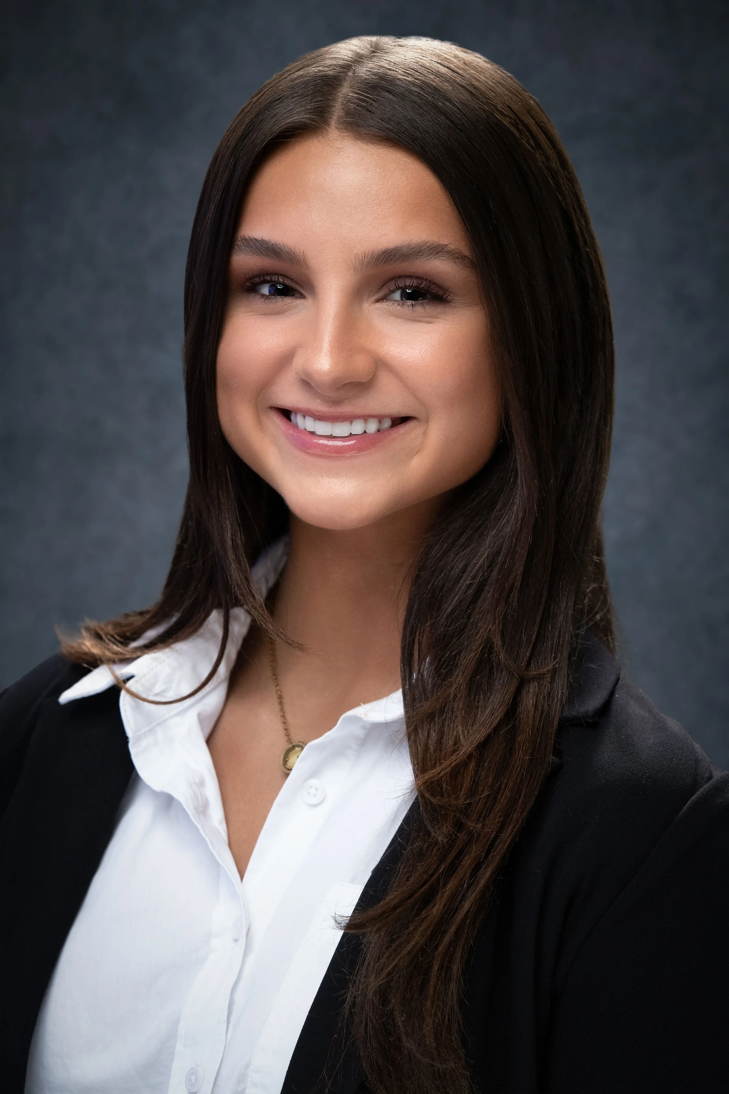 Corporate studio portrait of a business professional conveying approachability and confidence through natural expression and professional attire.