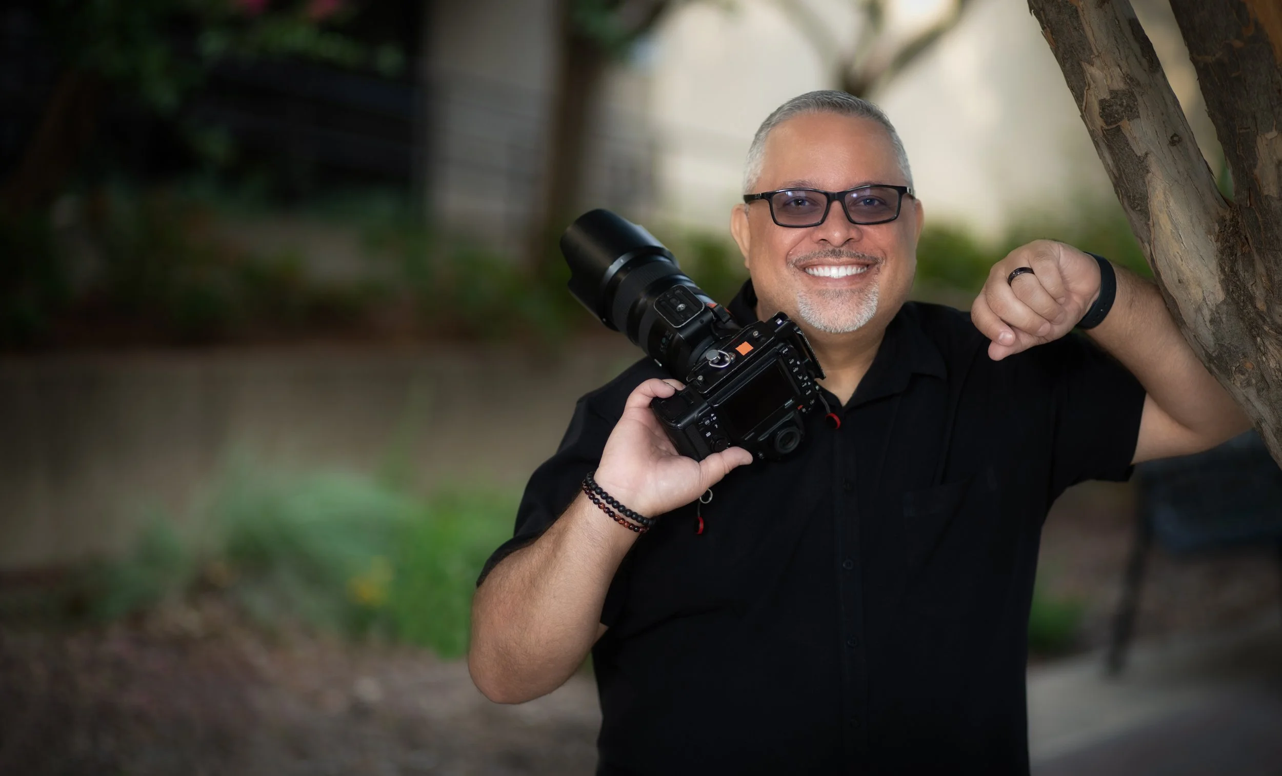 Professional photographer Hector Torres holding a camera during an on-location portrait session in the Dallas–Fort Worth area.