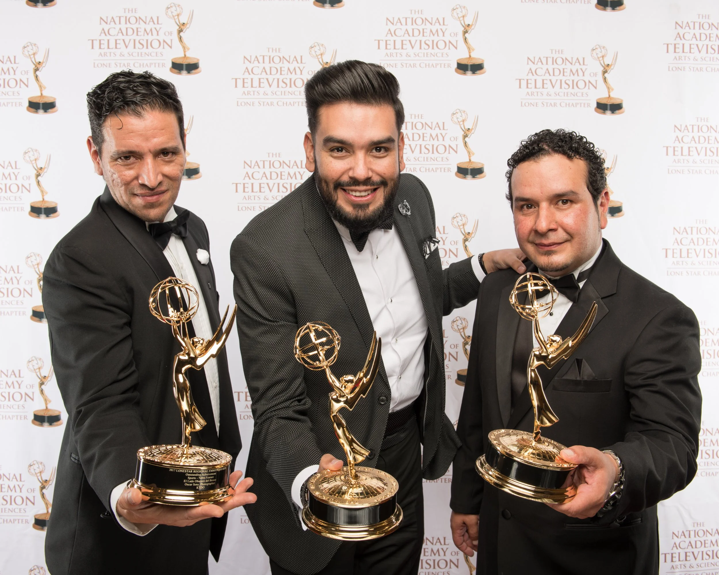 Three Emmy Award winners stand together holding their trophies, smiling confidently during a red-carpet portrait at the National Academy of Television Arts & Sciences Lone Star Chapter awards ceremony.