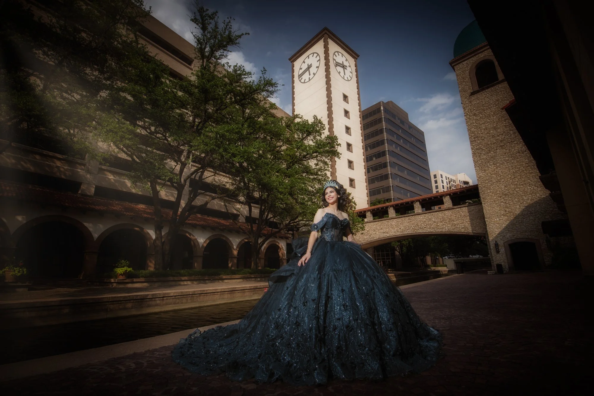 Luxury Quinceañera portrait in dark gown with city architecture and clock tower background