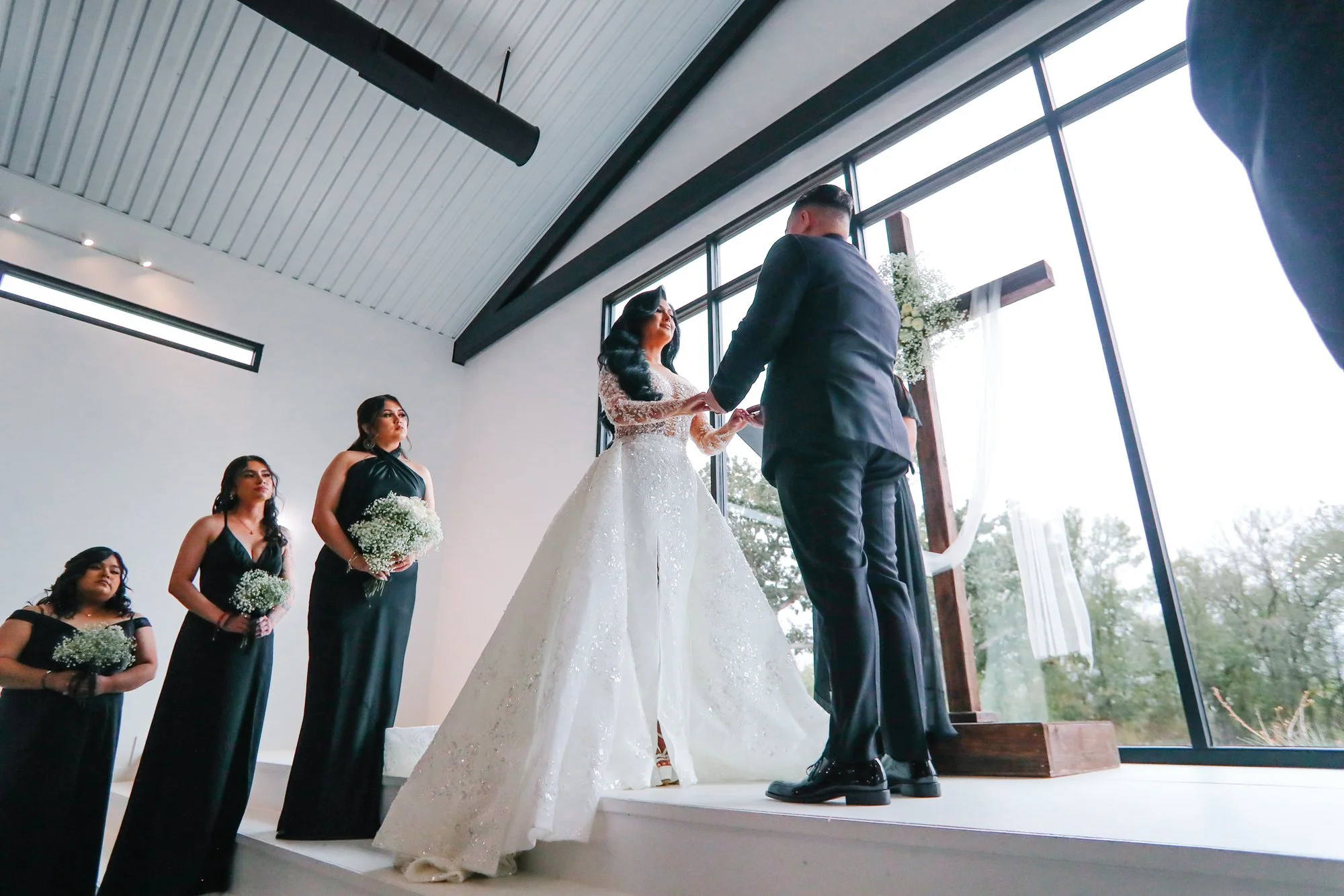 Karen and Matthew exchange their wedding vows beneath a beautiful cross during their modern wedding ceremony, photographed by Hector Torres Photography.